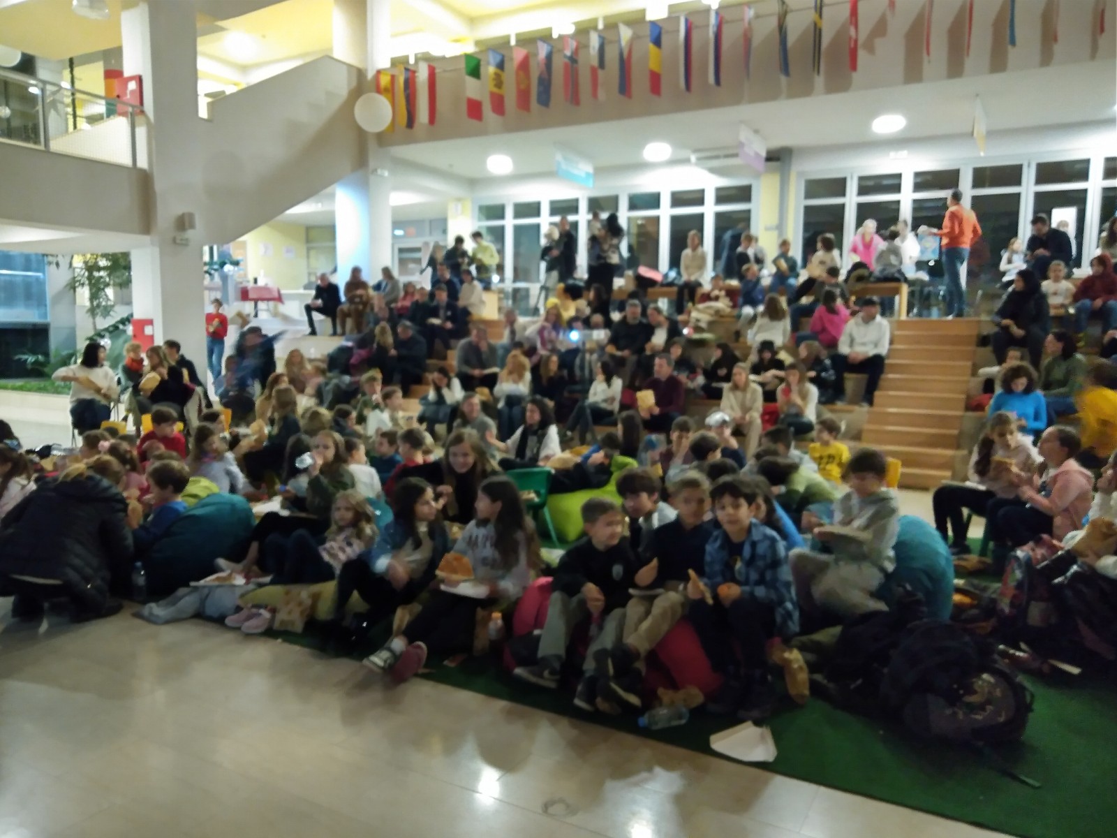 Elementary students sitting together in the atrium for movie night