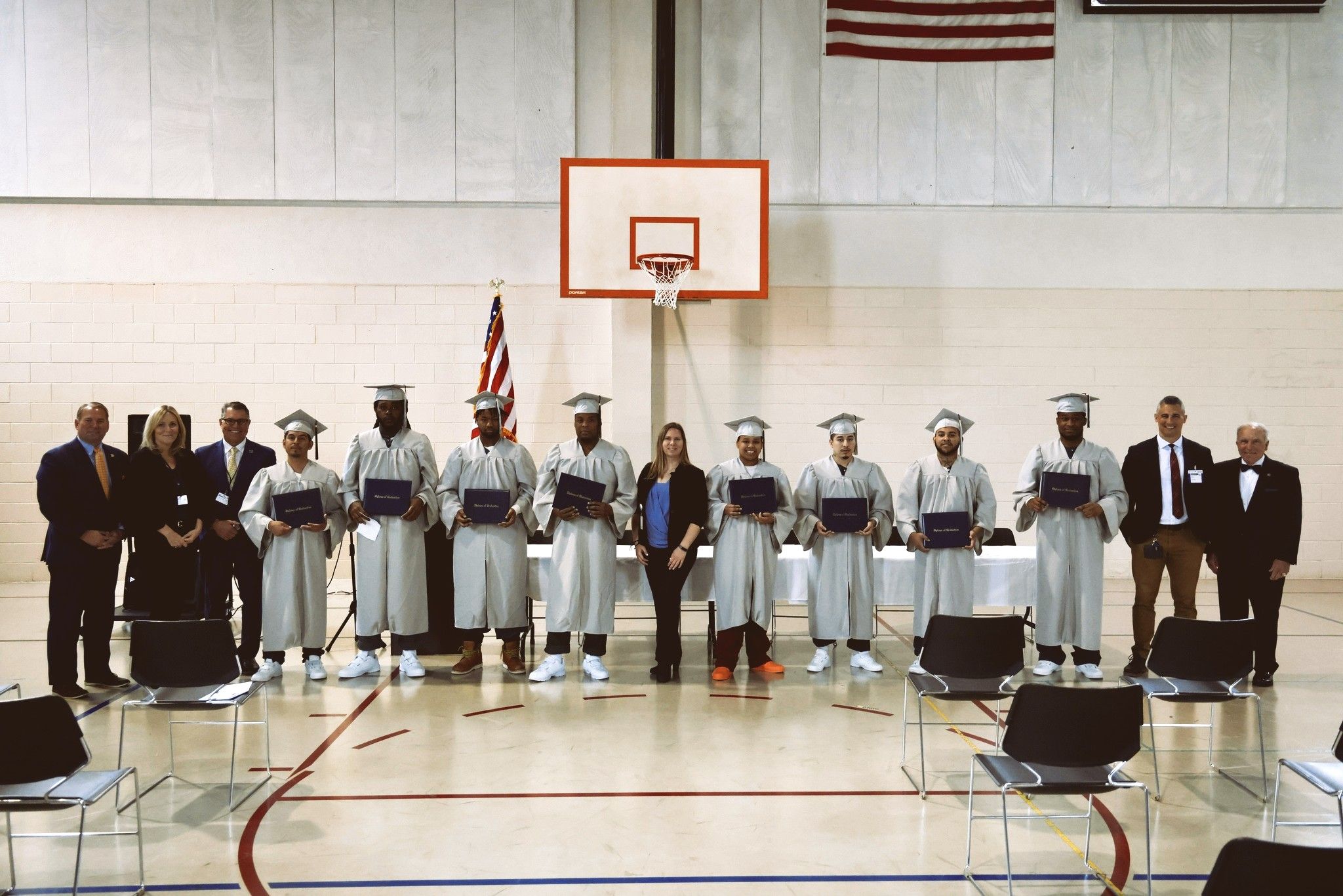 A photo of graduates wearing cap and gowns in a gymnasium 