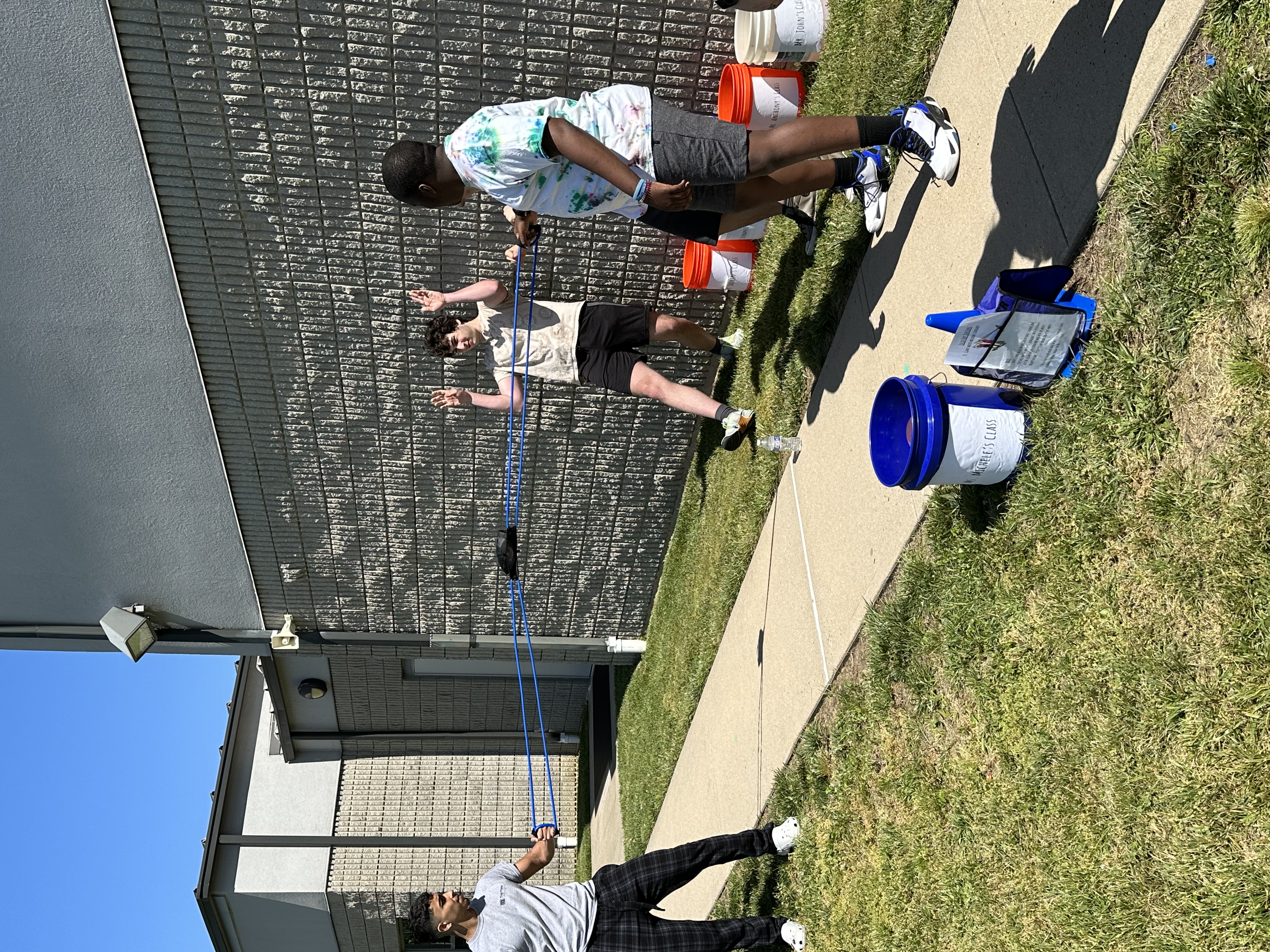A trio of students experimenting with a sling shot