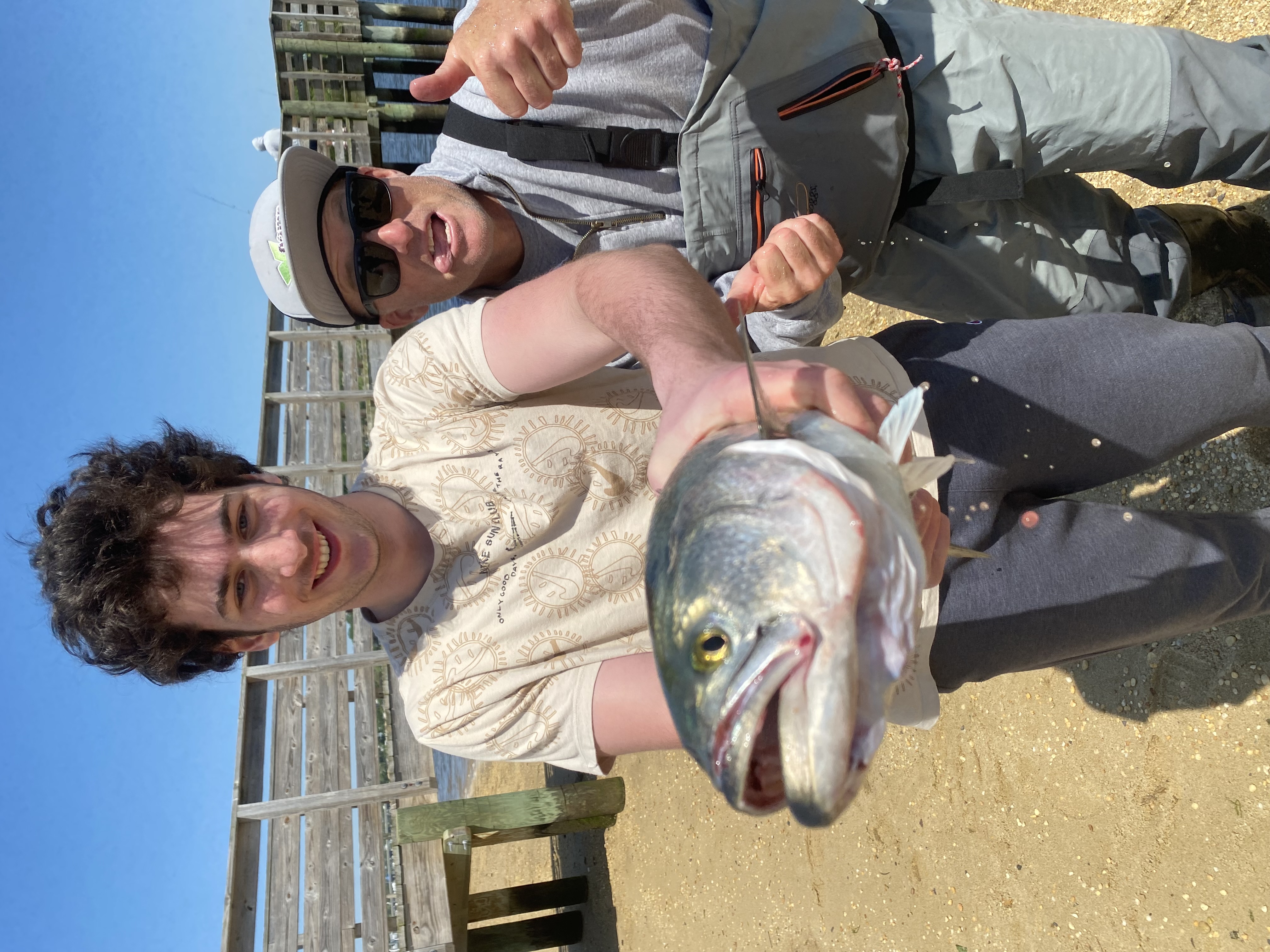 student and instructor pose during a fishing excursion holding a fish