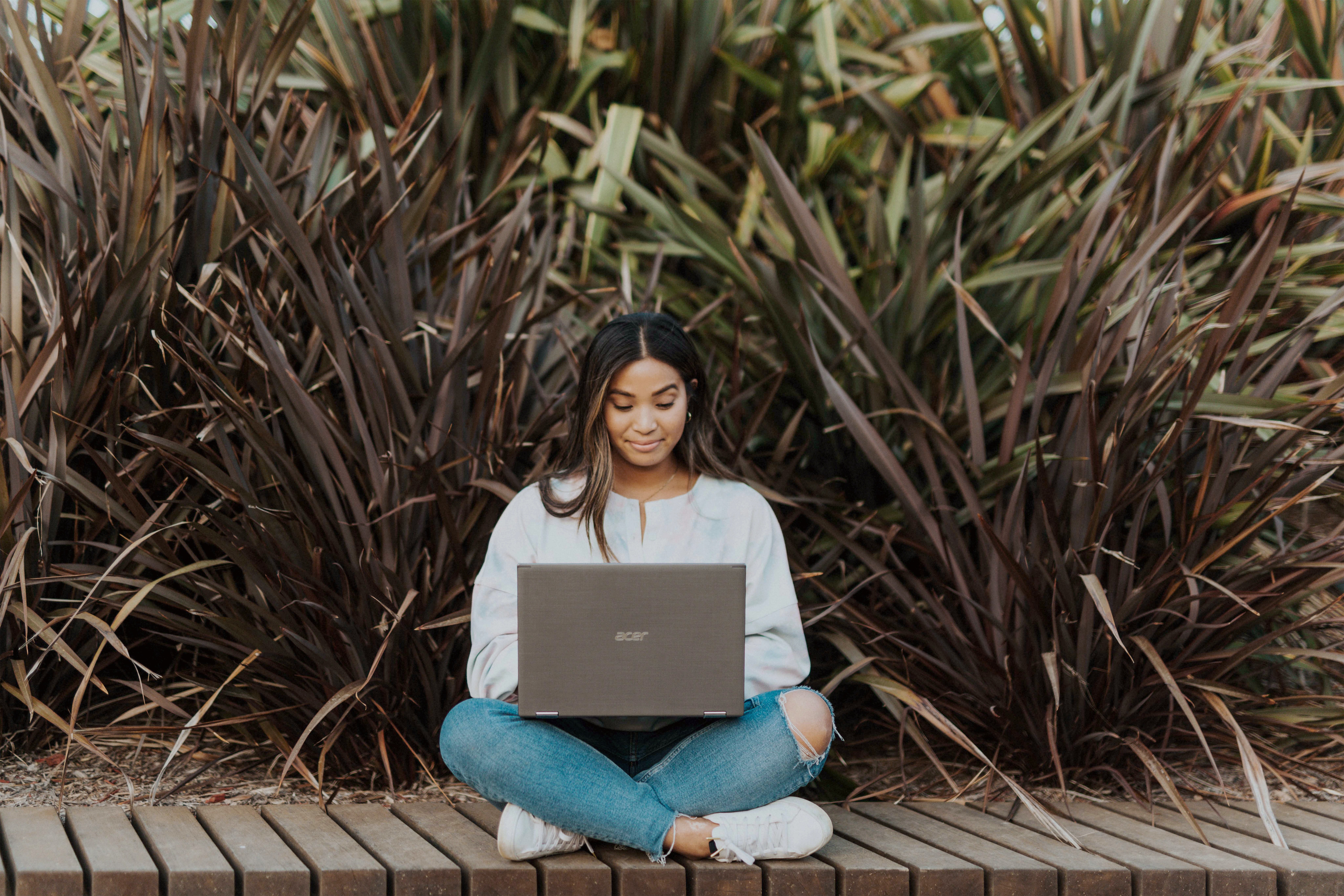 Girl on laptop in nature sitting cross legged