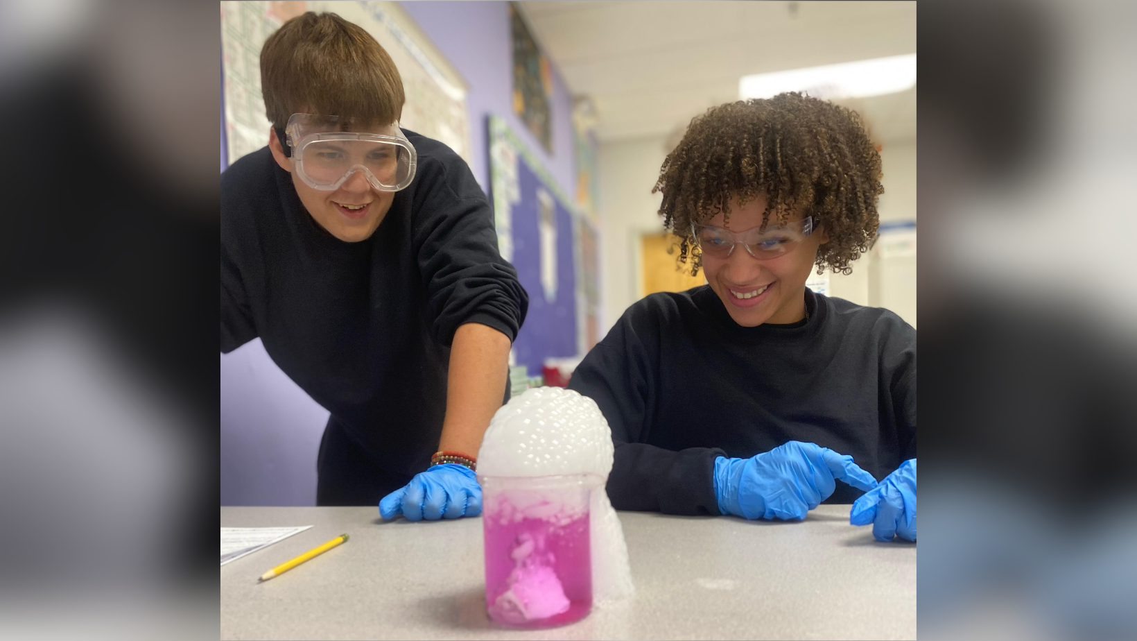 Students smiling while watching a science experiment