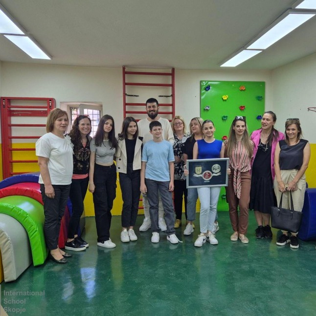 NOVA staff and students posing with a donation plaque in a sensory room