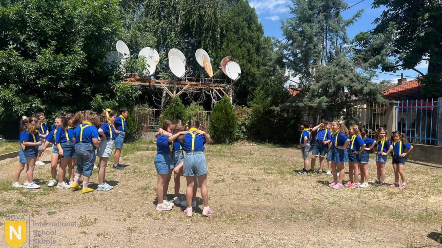 Students in blue and yellow performing a group dance outdoors
