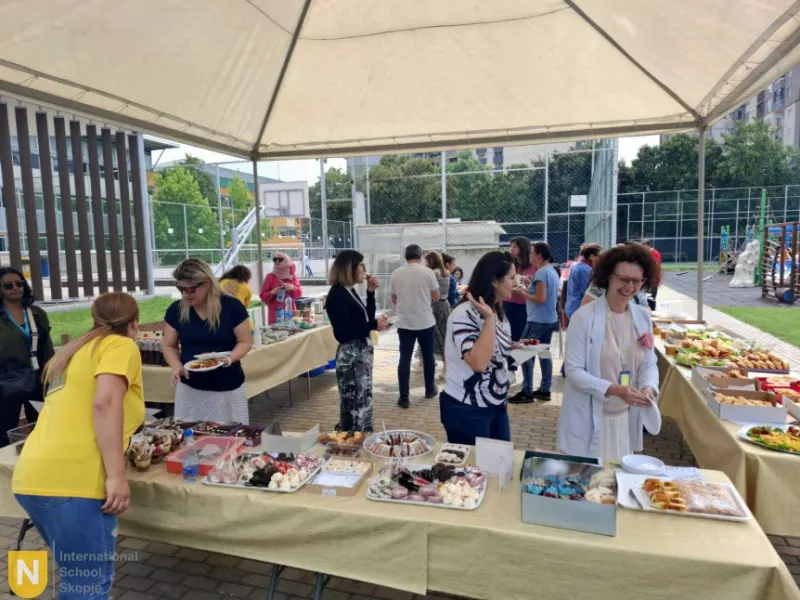 Parents at tables of homemade treats under a tent at a PTA bake sale