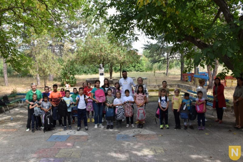 Group of children and adults posing outdoors during a PTA visit to a village school