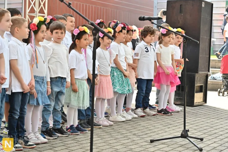 Young students in flower crowns singing on stage at an outdoor performance