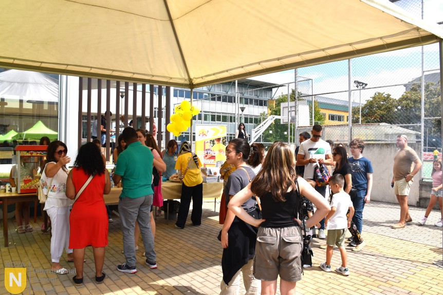 Families visiting food stalls under canopies at the BBQ social