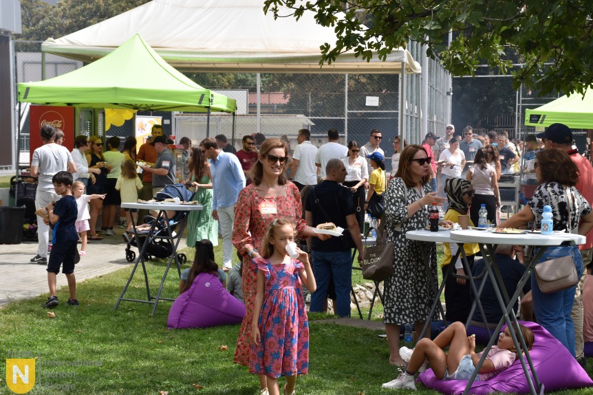 Families gathered on the lawn by the green tents at the BBQ social