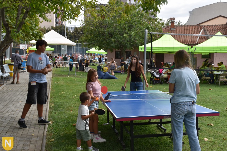 Families playing table tennis on the school lawn at the BBQ social