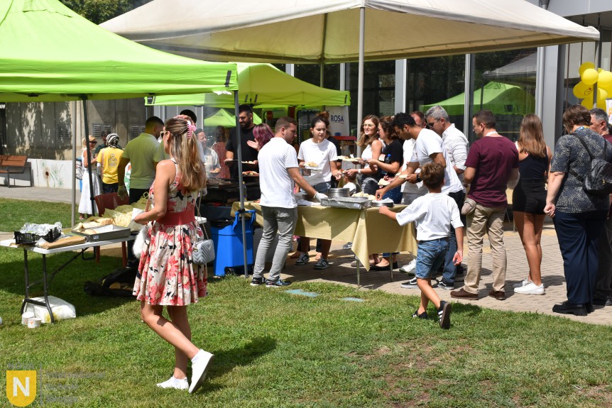 Guests serving themselves at food tables under green tents at the BBQ social