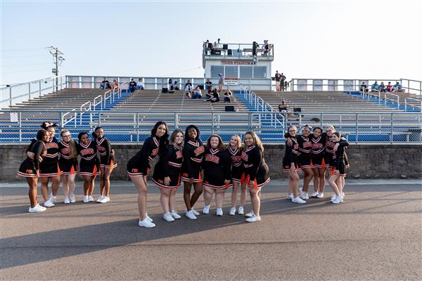 cheerleaders in formation on track with bleachers in background