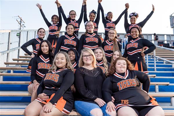 cheerleaders in black uniforms in front of bleachers
