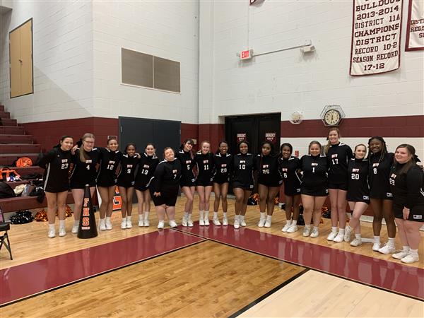 cheerleaders in row on sideline wearing black uniforms