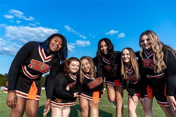 group of cheerleaders looking down with blue sky behind