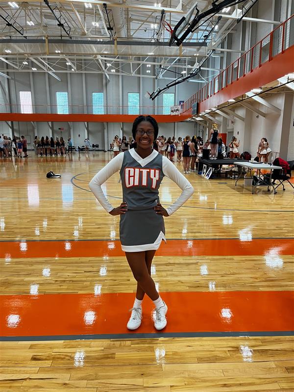 single cheerleader in gray uniform in gym