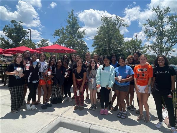 students in a group with trees and blue skies behind