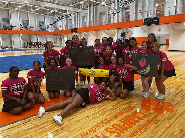 cheerleaders holding inflatable banana in gym