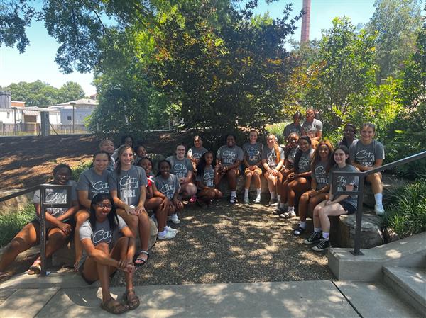 cheerleaders in gray shirts seated on brick walls