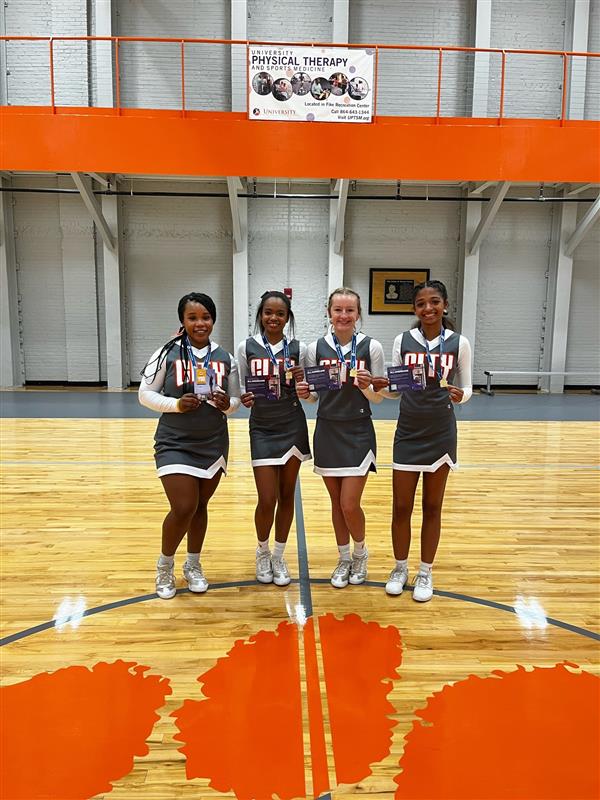 cheerleaders in gray uniforms holding awards