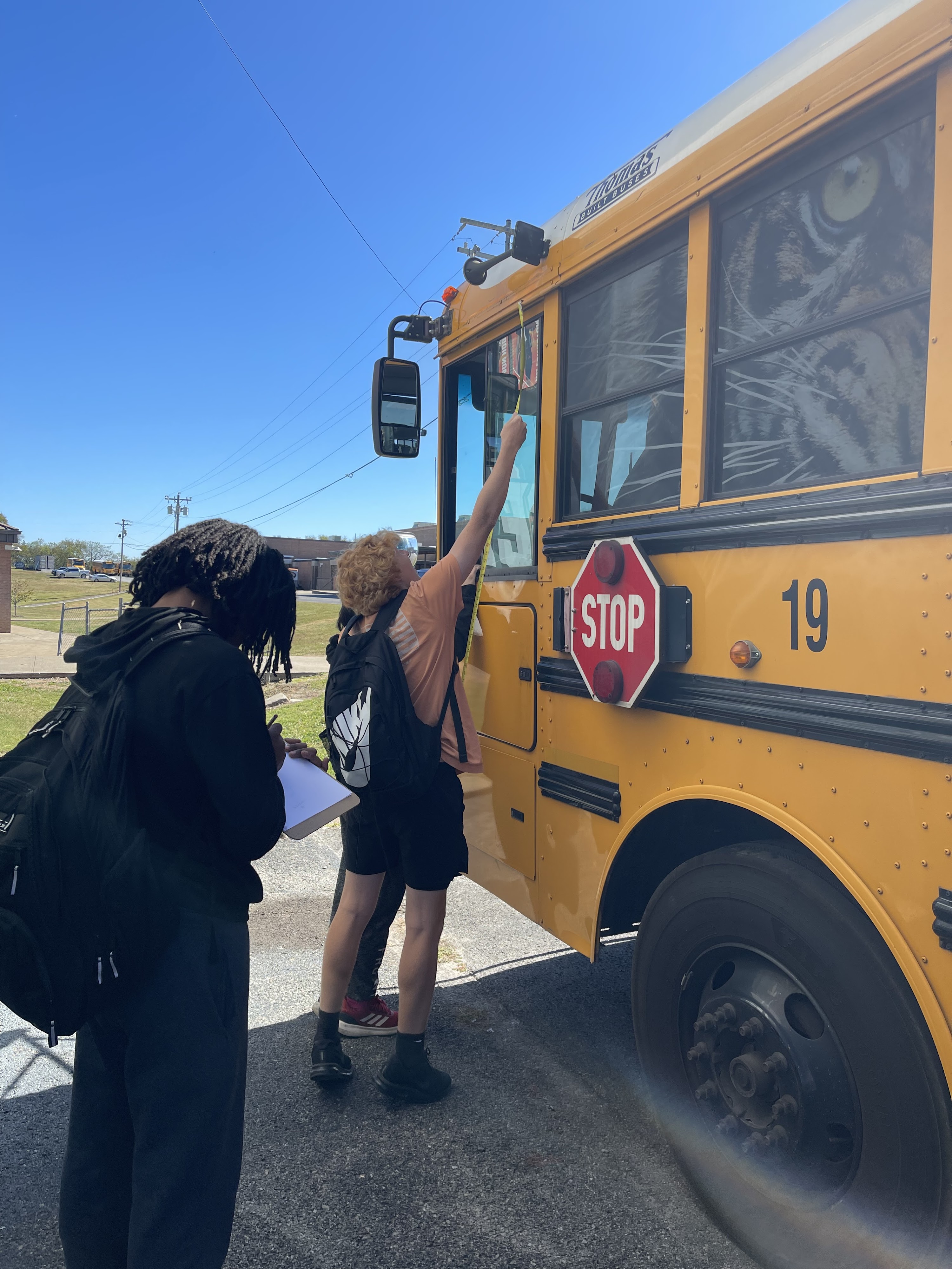 students taking measurements of bus