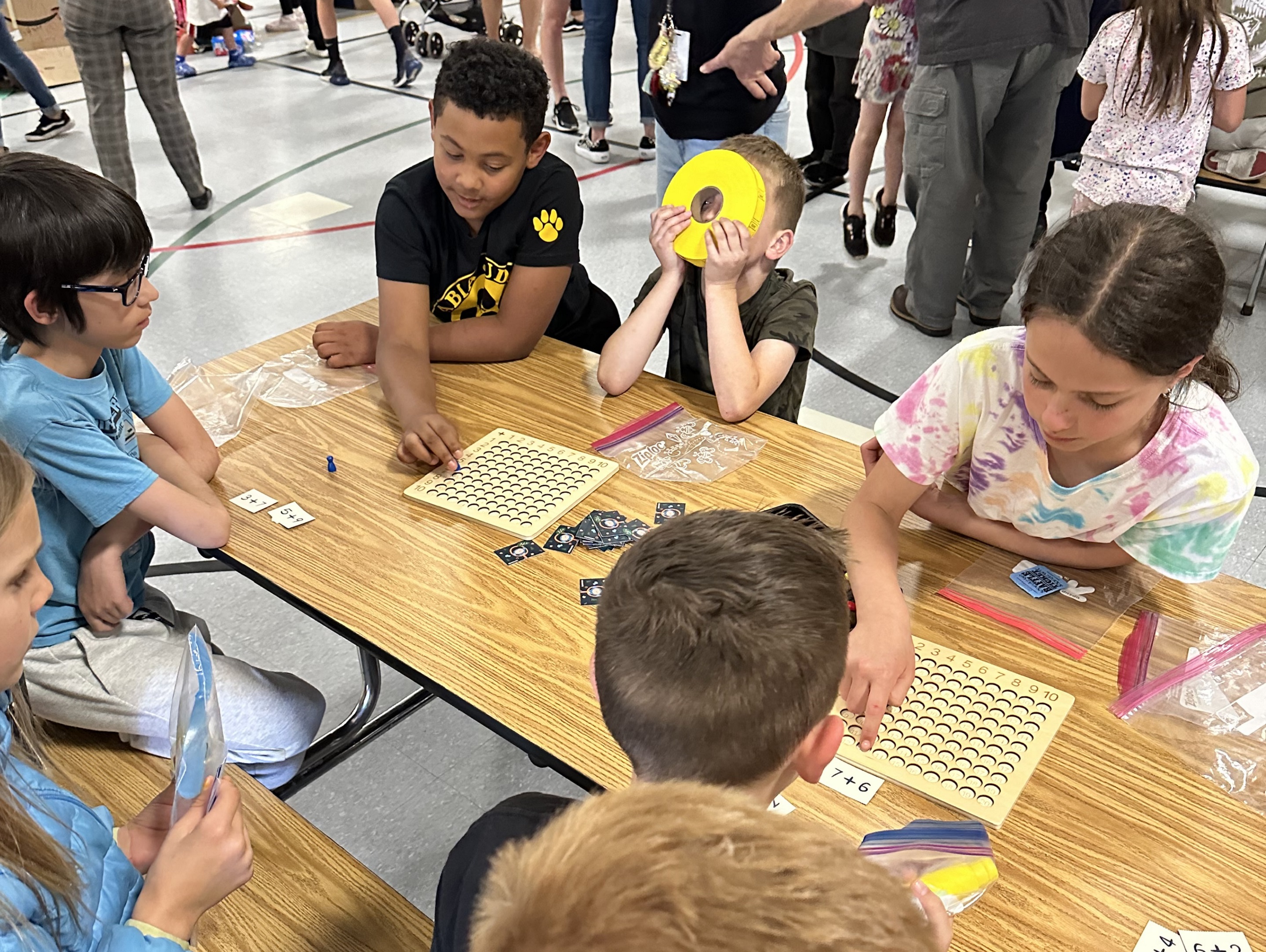 Students at the arcade play math games at the arcade night.  One student holds a roll of tickets for the games.