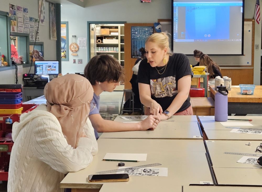 photo of art teacher helping student with drawing