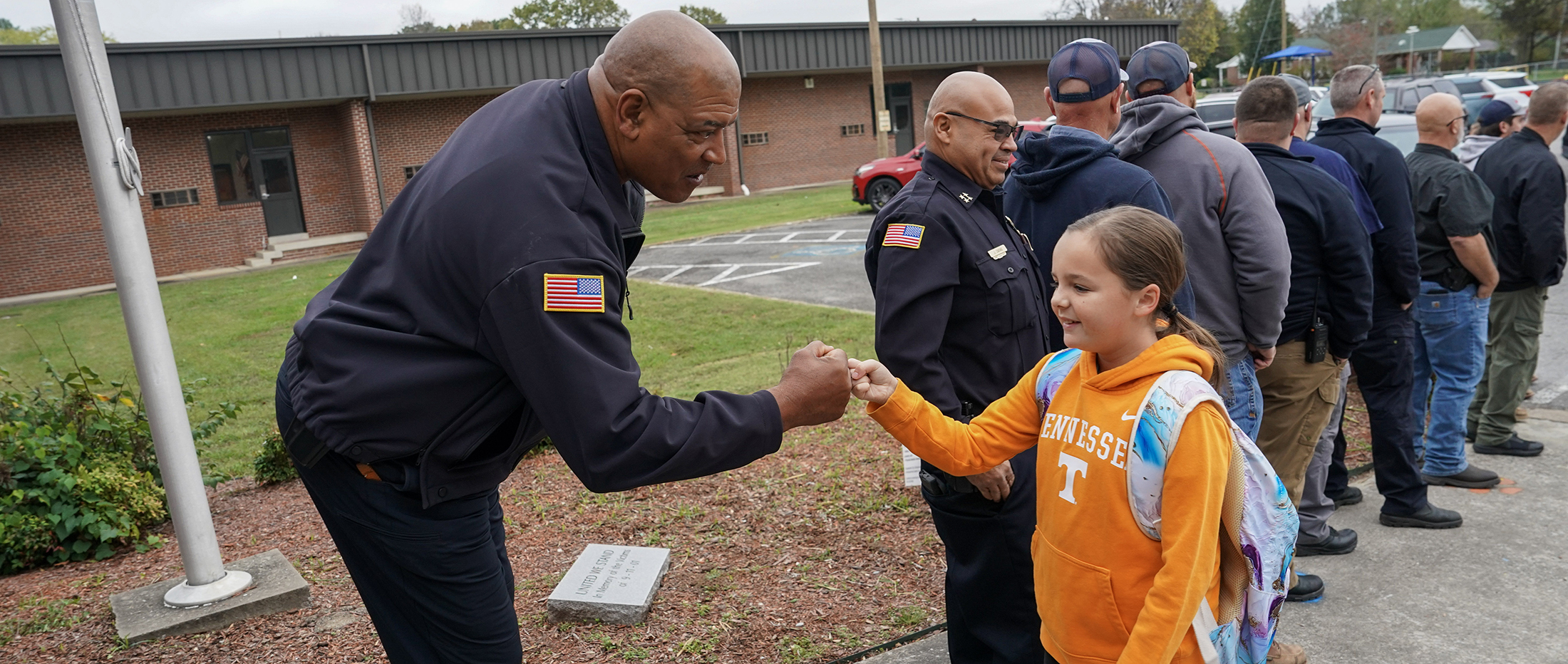 police offer giving fist bump to young student with backpack