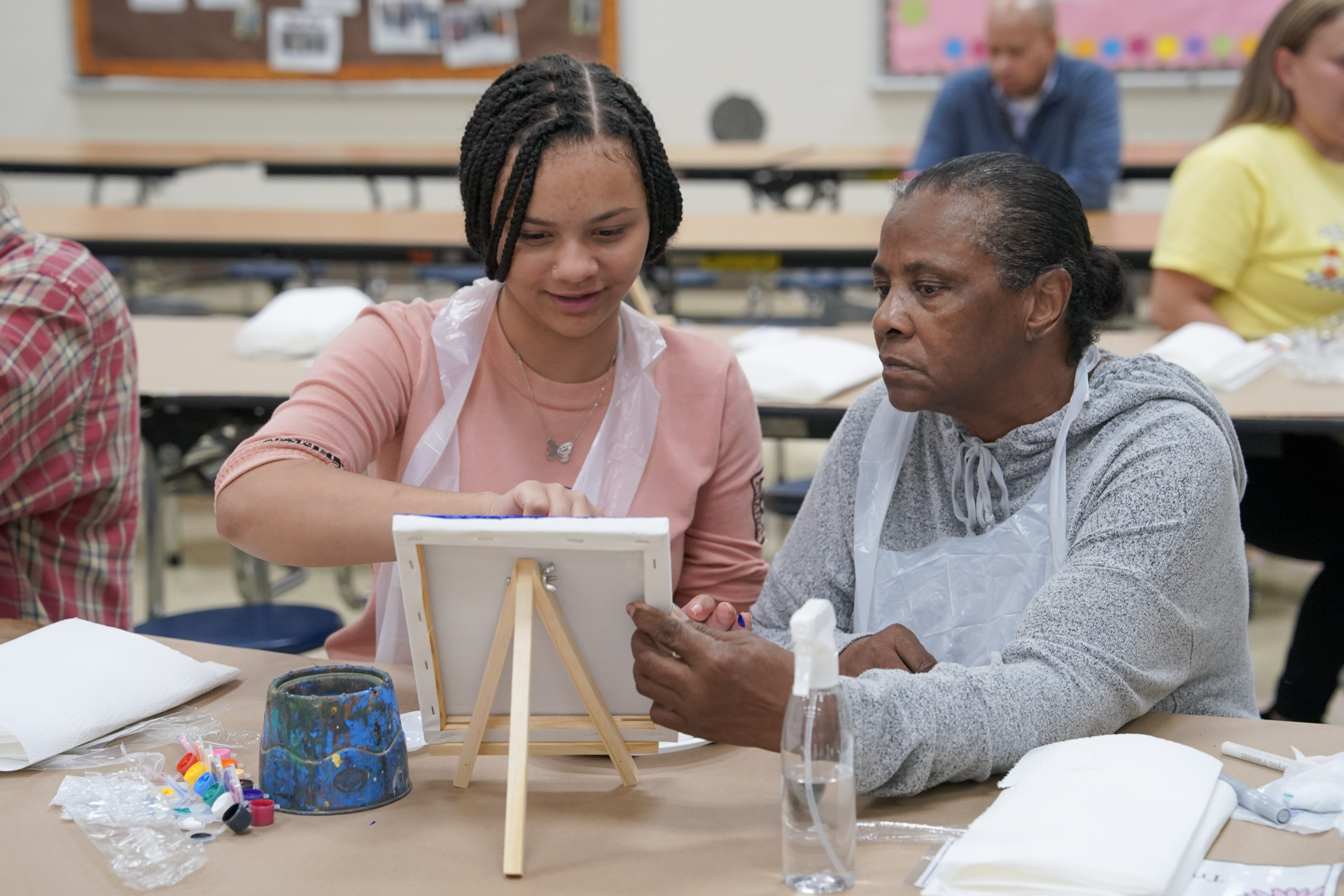 Student seated at table painting on canvas
