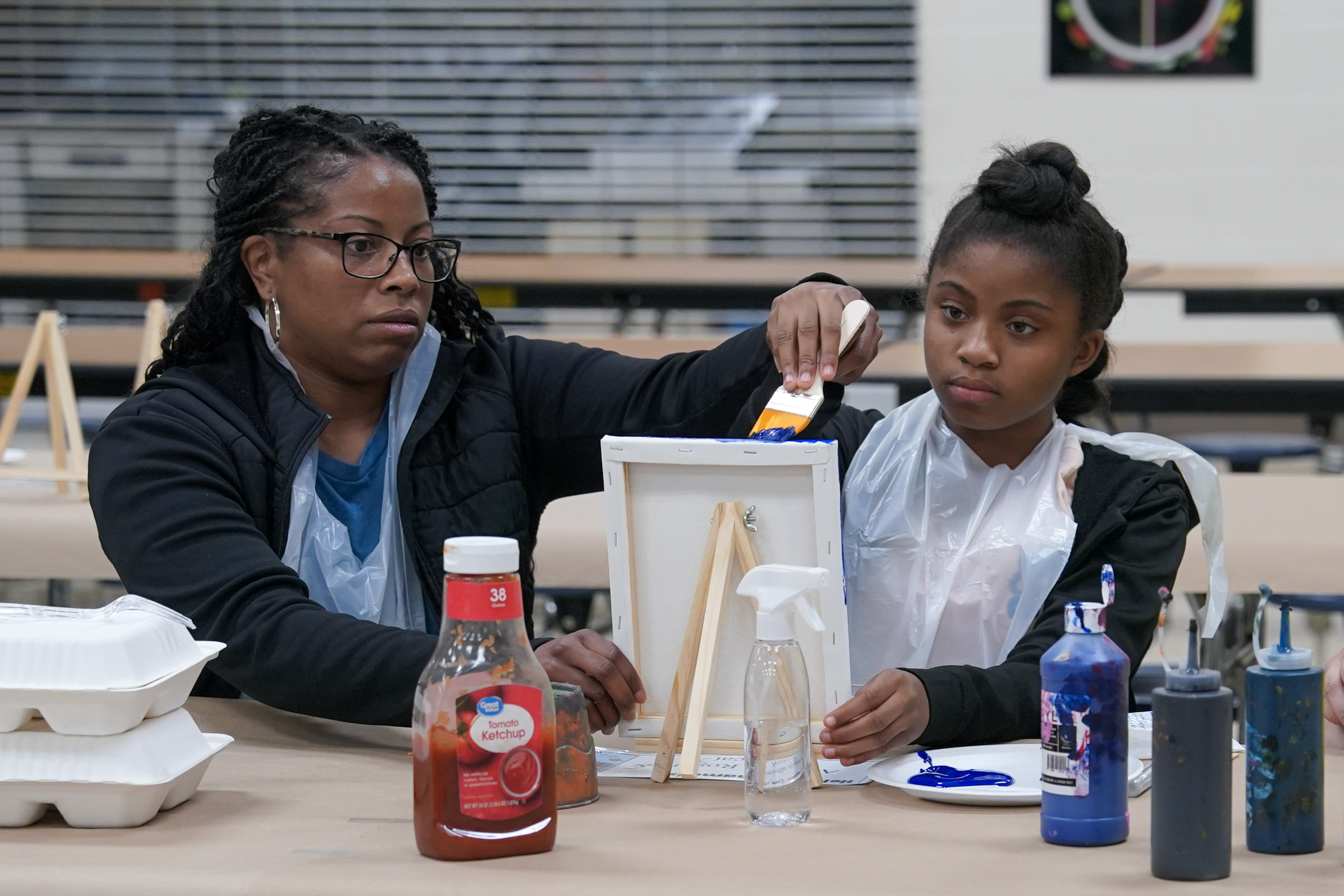 Student seated at table painting on canvas