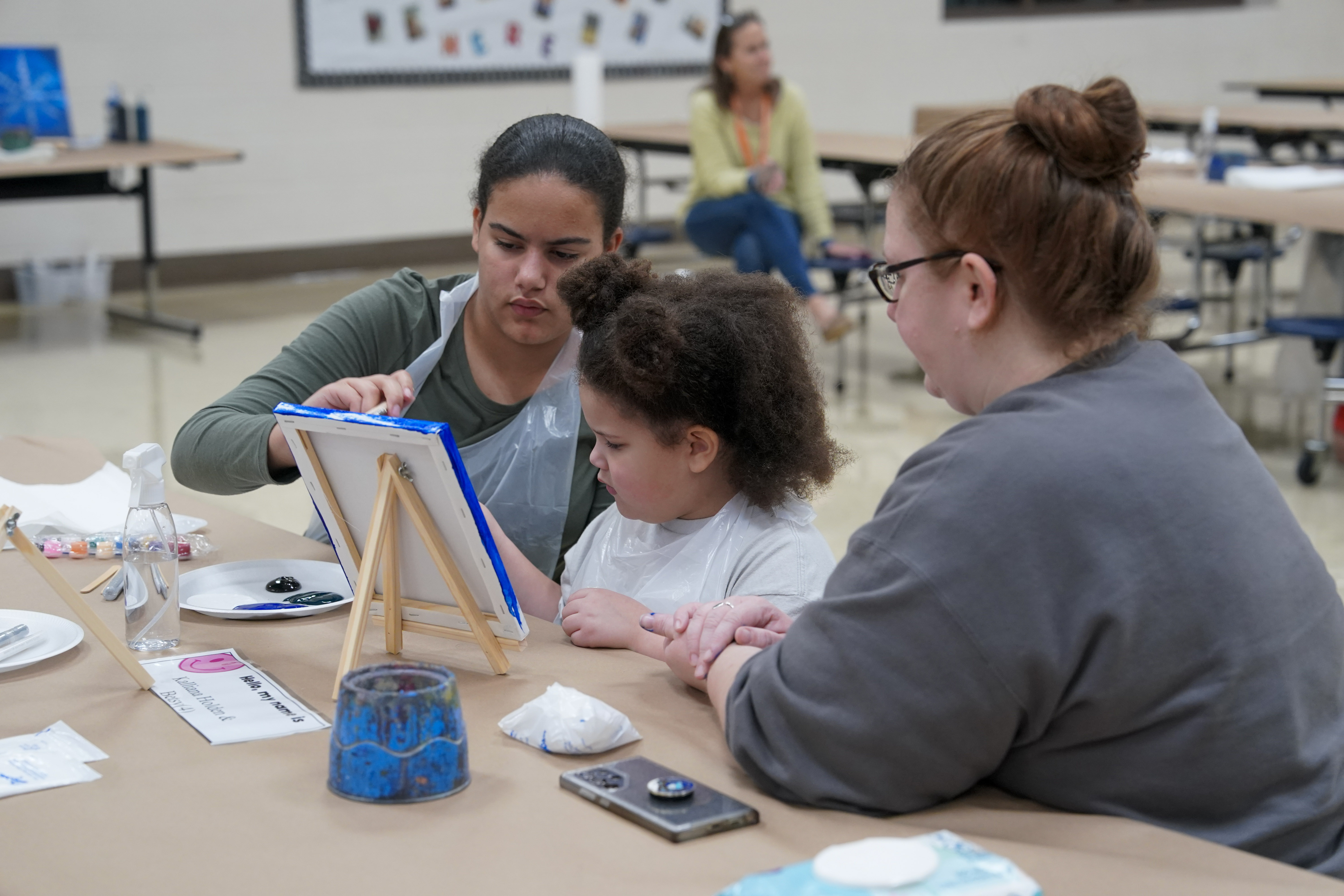 Student seated at table painting on canvas