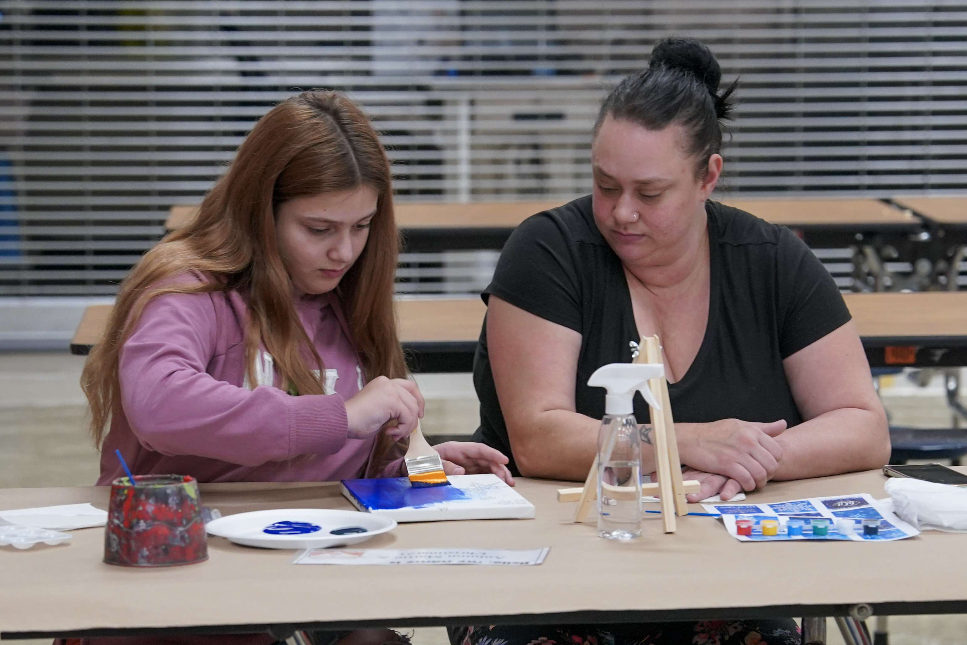 Student seated at table painting on canvas