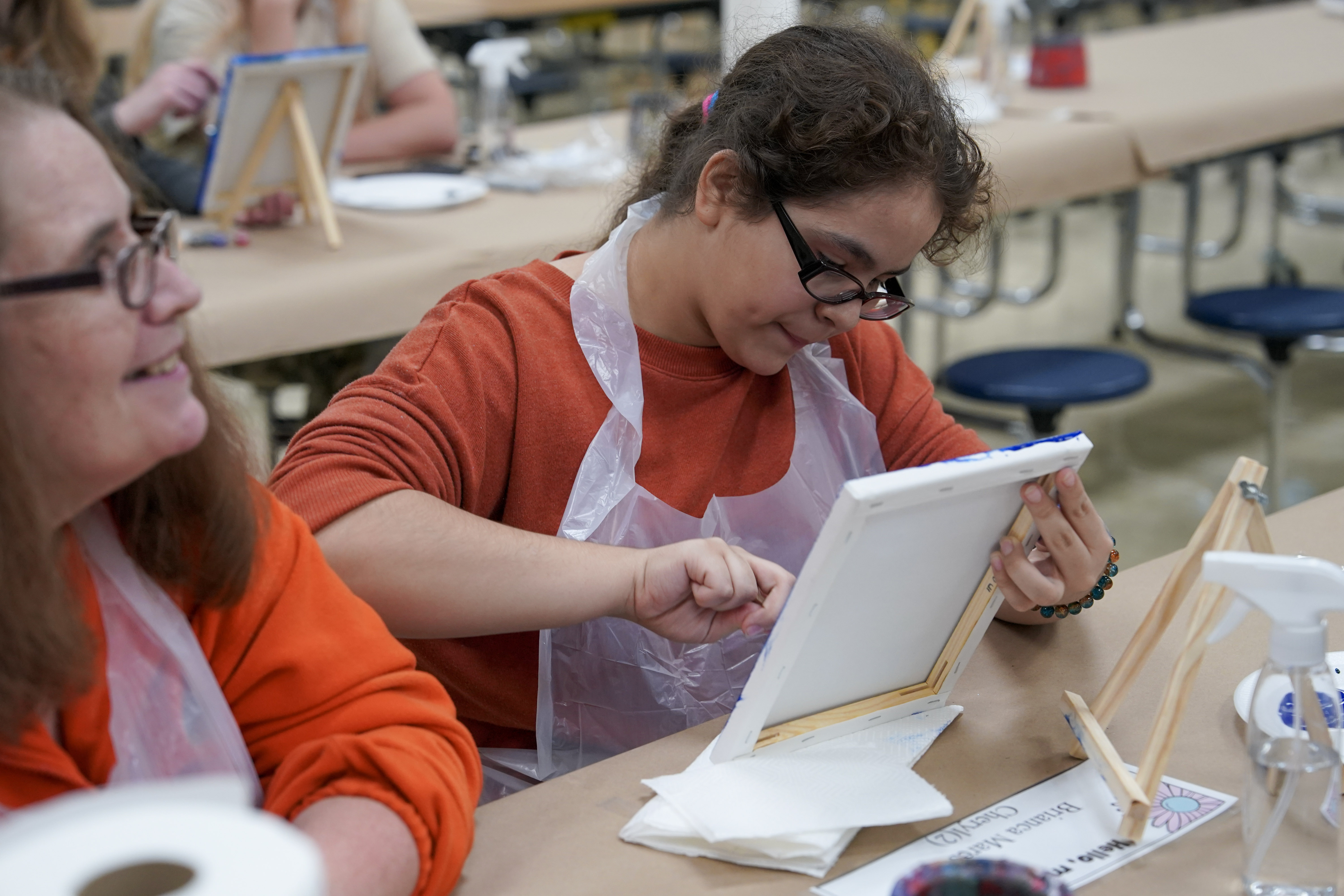Student seated at table painting on canvas
