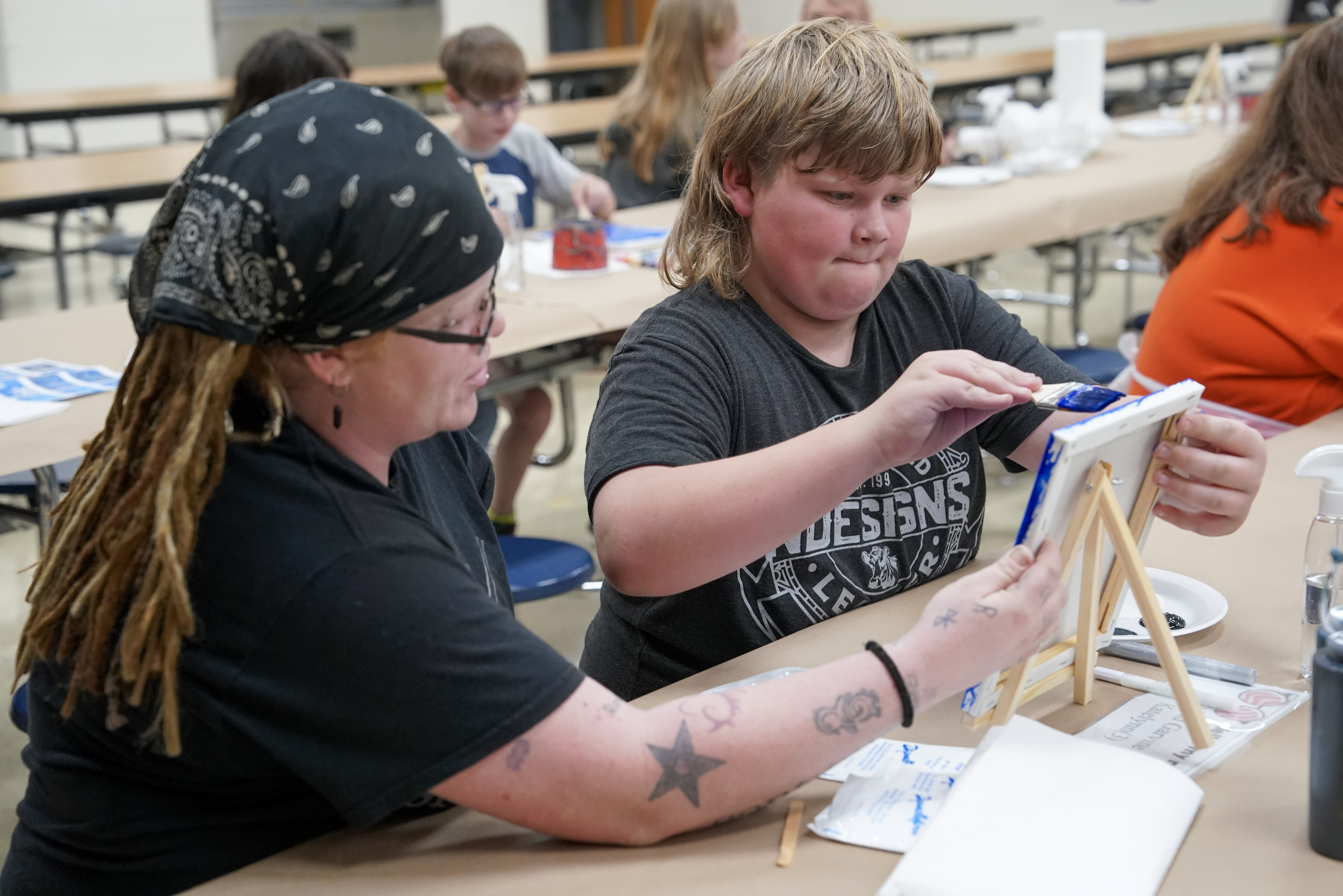 Student seated at table painting on canvas