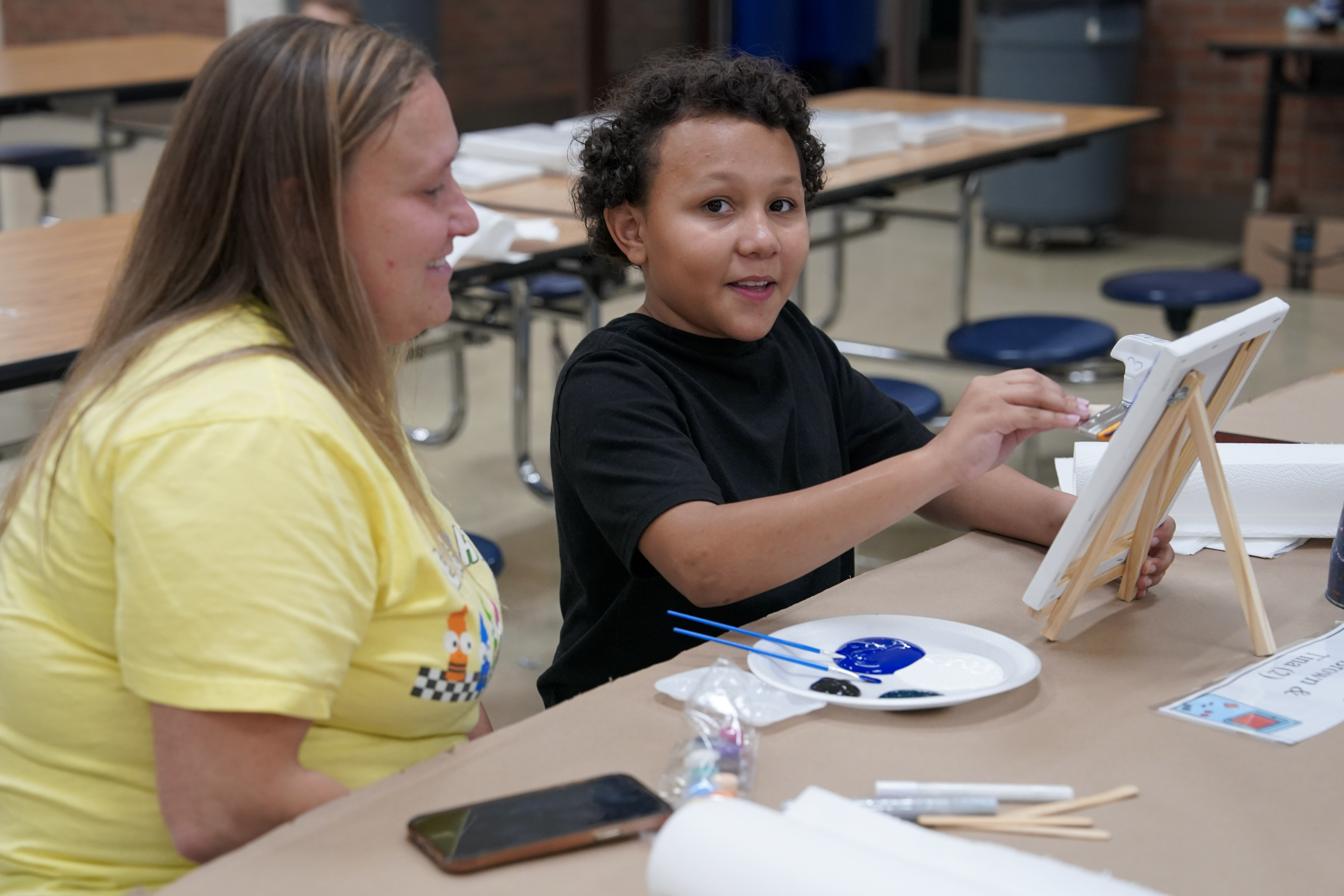 Student seated at table painting on canvas