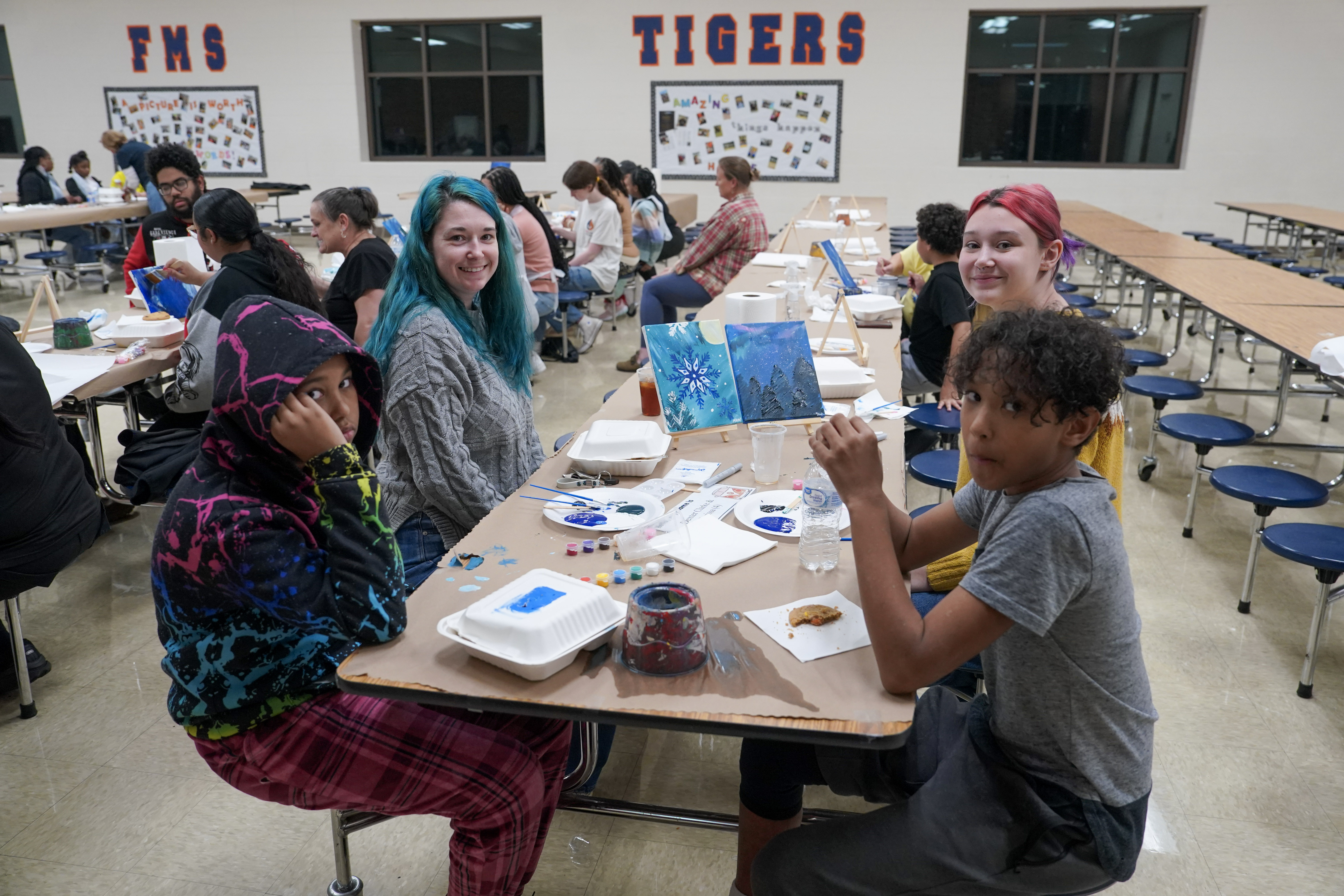 Students seated at table painting on canvas