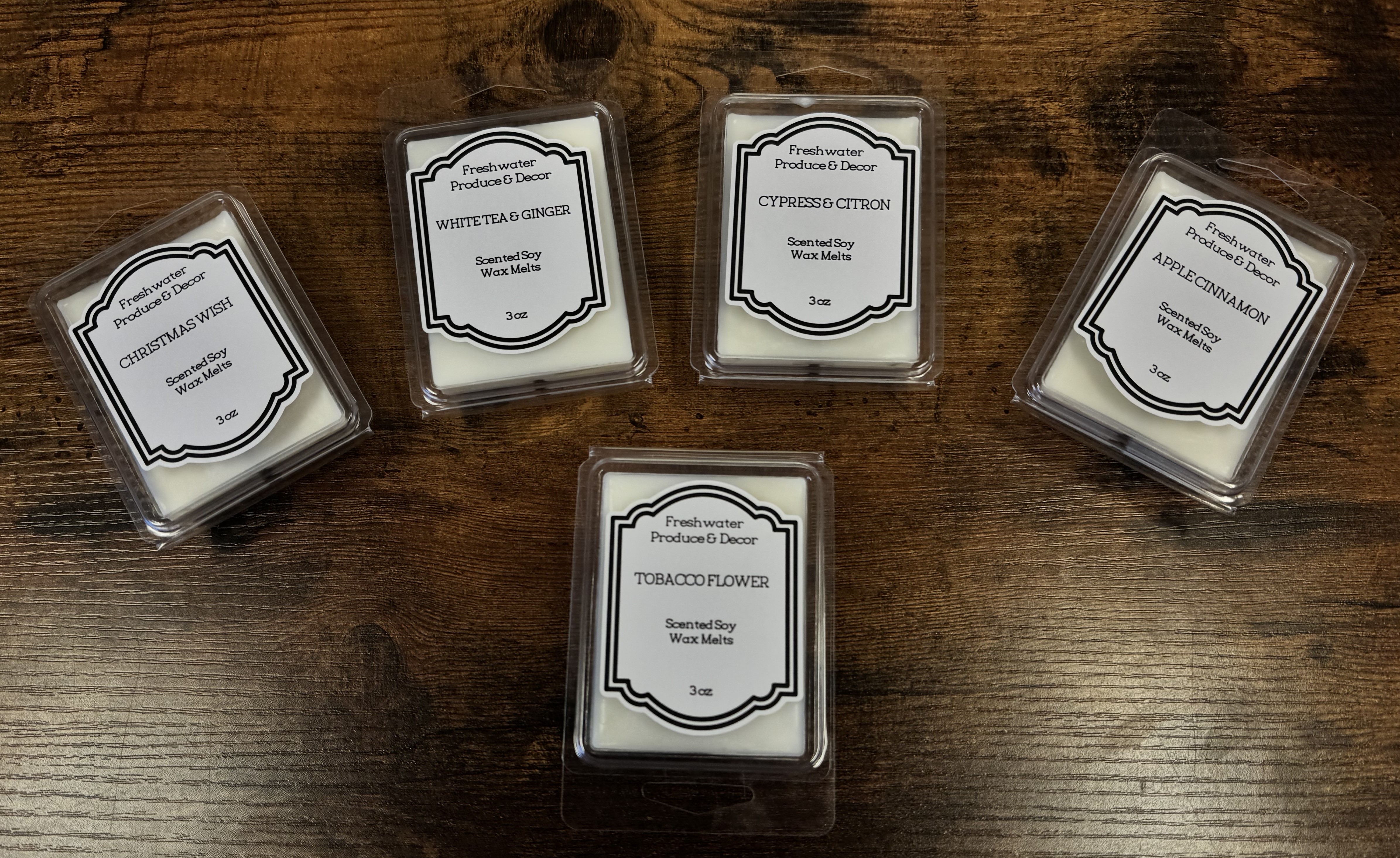 The image shows several rectangular glass containers with white labels on a wooden surface.