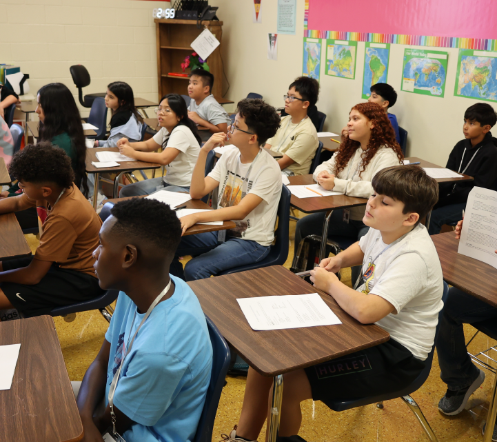 A classroom setting with students seated at desks, engaged in various activities, and the walls decorated with colorful artwork and educational materials.