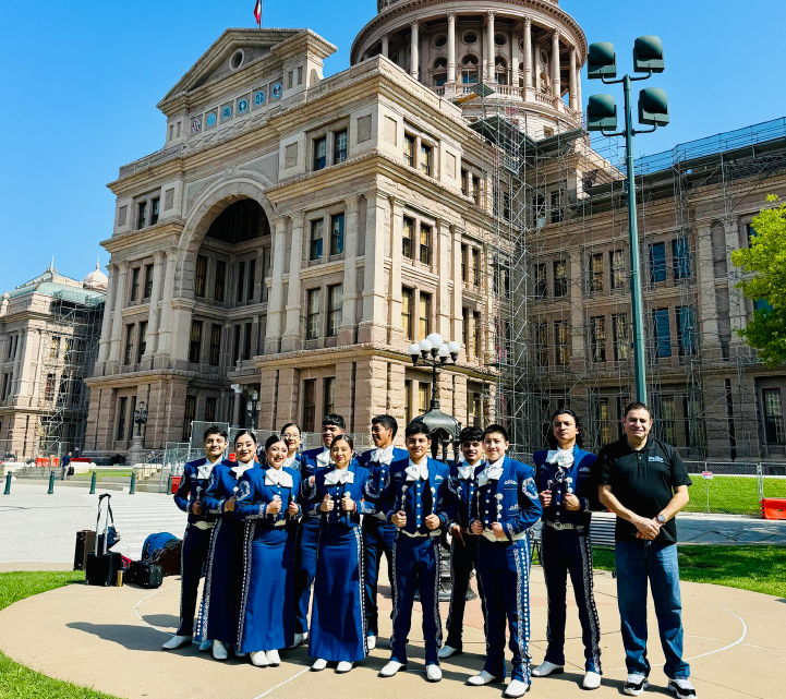 A group of people in blue uniforms standing in front of a grand, ornate government building with a dome on top.