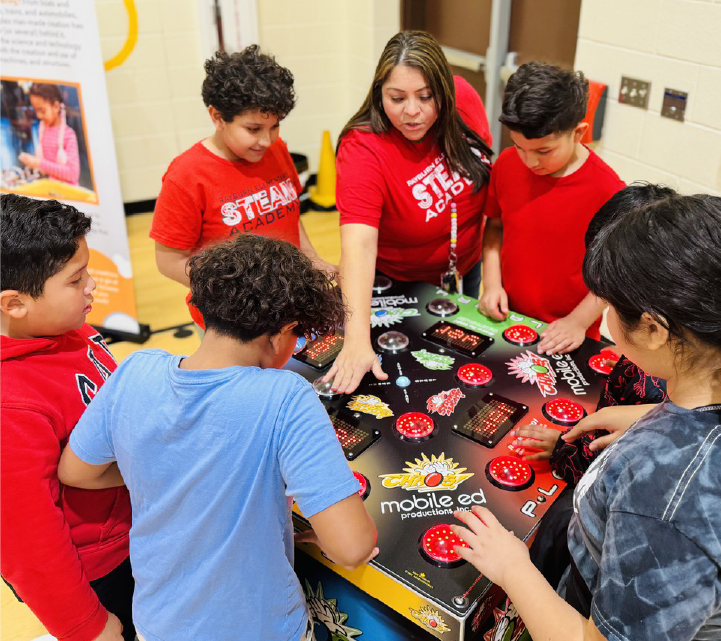 A group of young people in red shirts are gathered around a table, engaged in an activity or discussion.