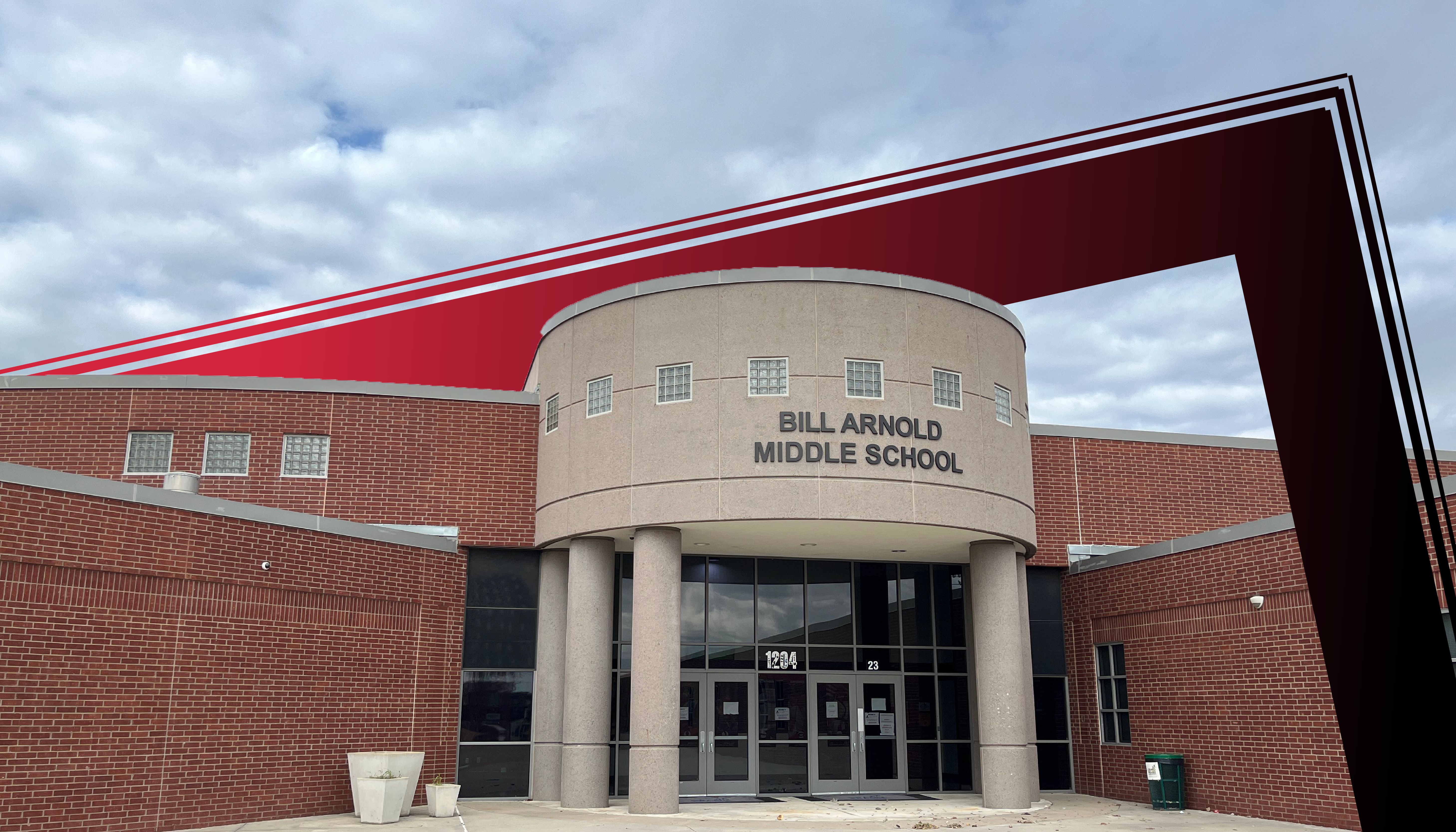A large brick building with a rounded entrance and the text "Billanold Middle School" displayed prominently on the facade, set against a cloudy sky background.
