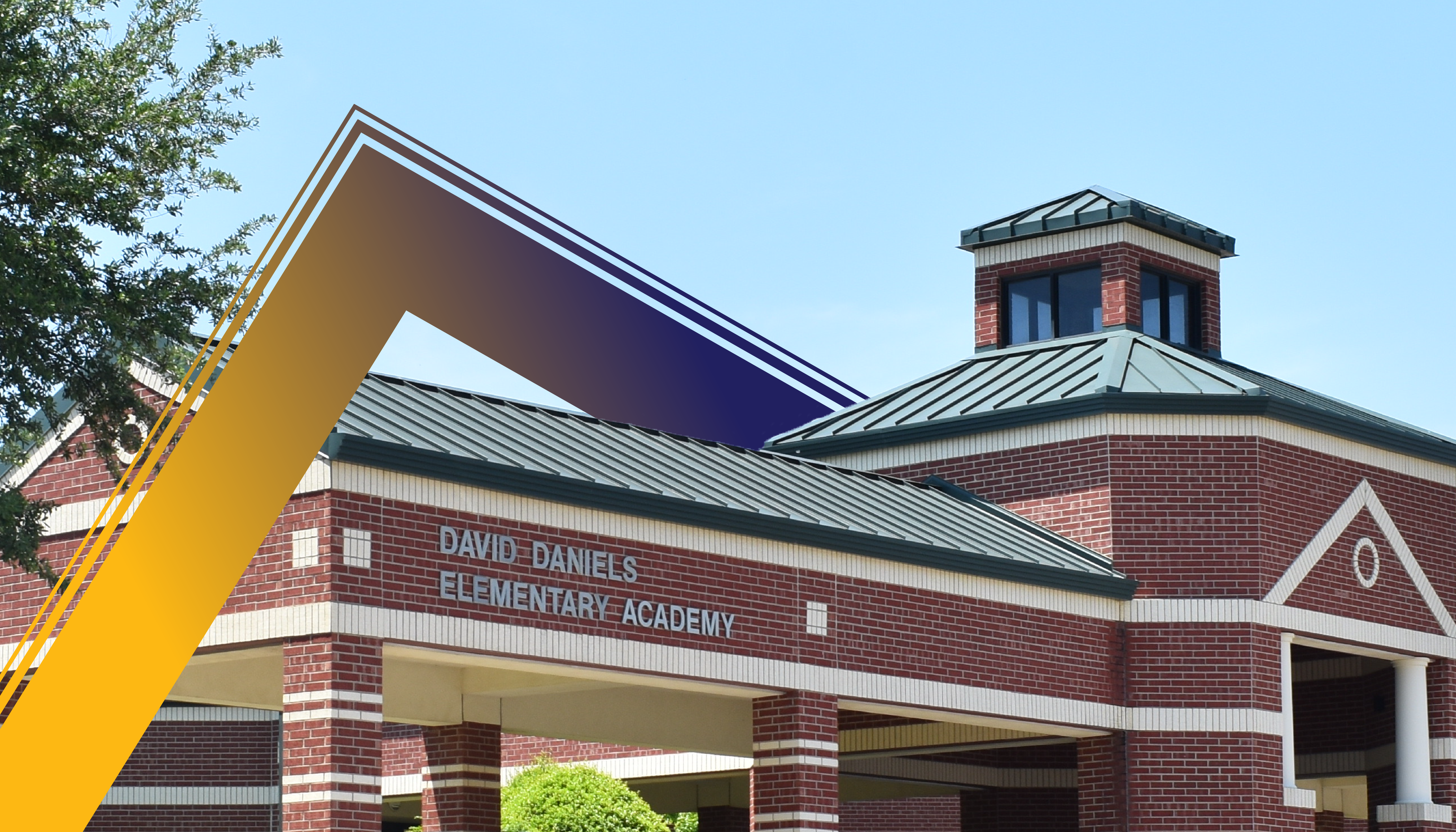 A brick building with a metal roof and a colorful, angular structure in the foreground, surrounded by trees against a clear blue sky.