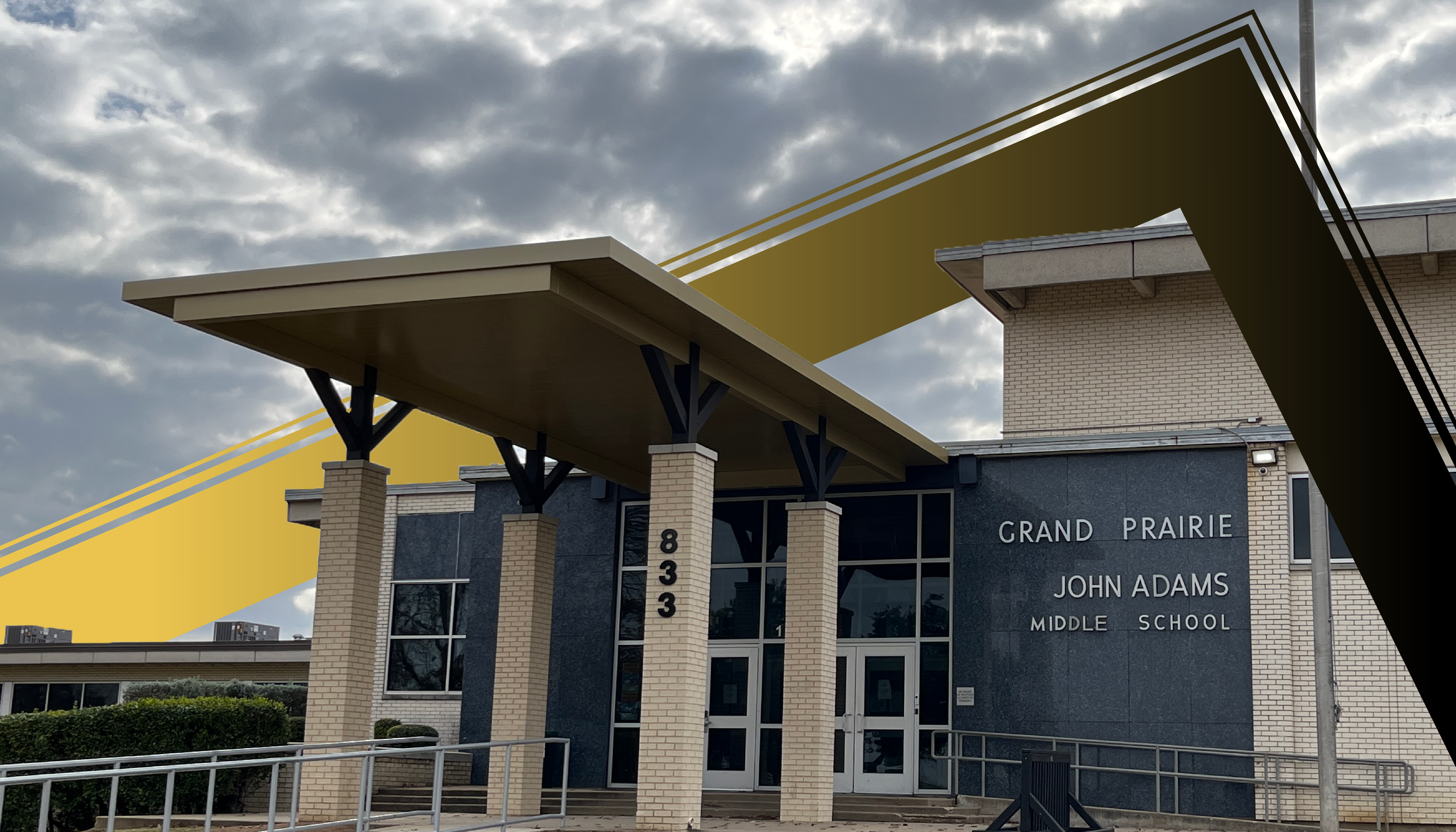 A modern, multi-story school building with a prominent yellow and gray exterior, set against a cloudy sky in the background.