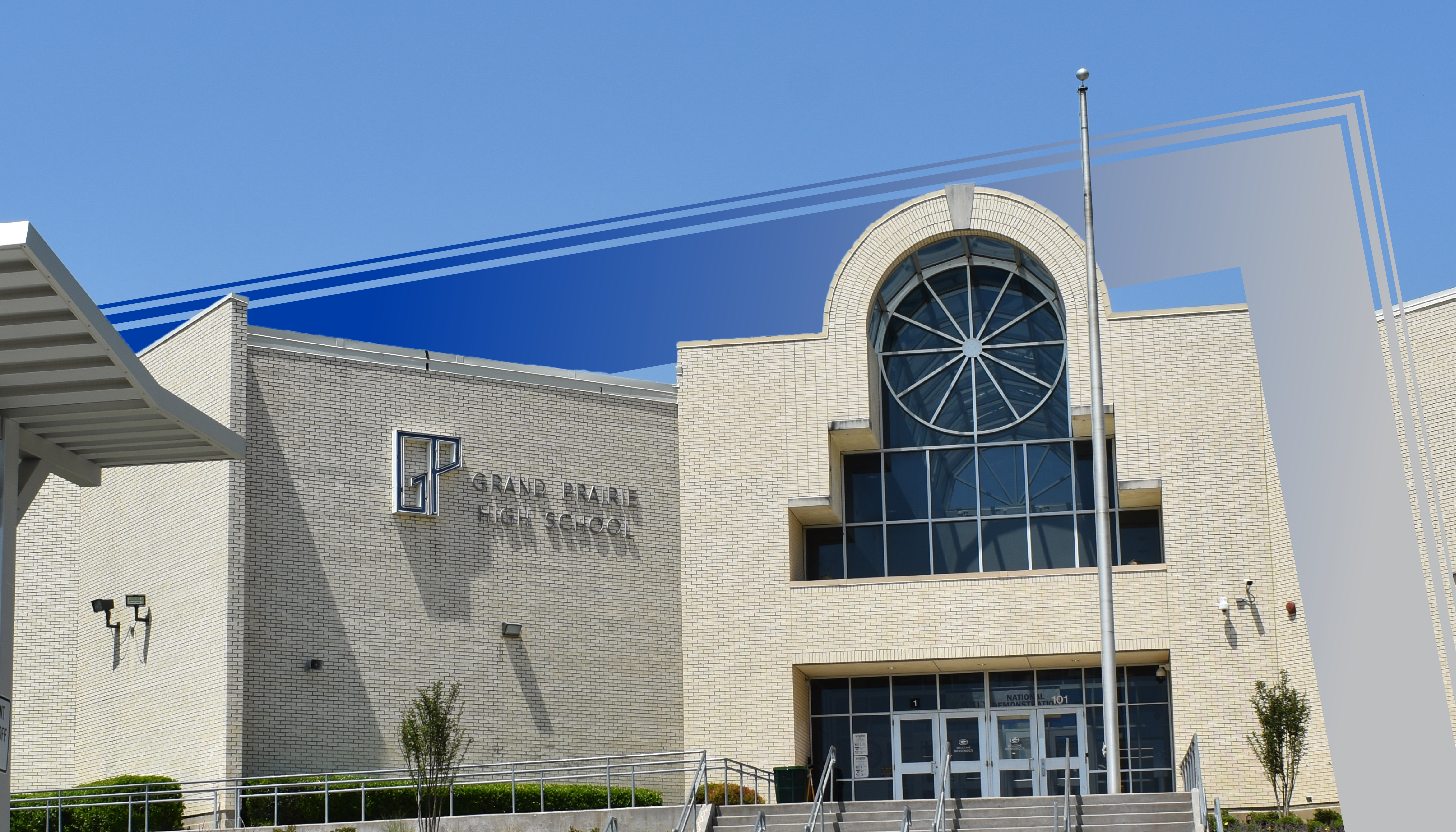 A large, modern building with a distinctive arched window and a blue exterior stands against a clear blue sky.