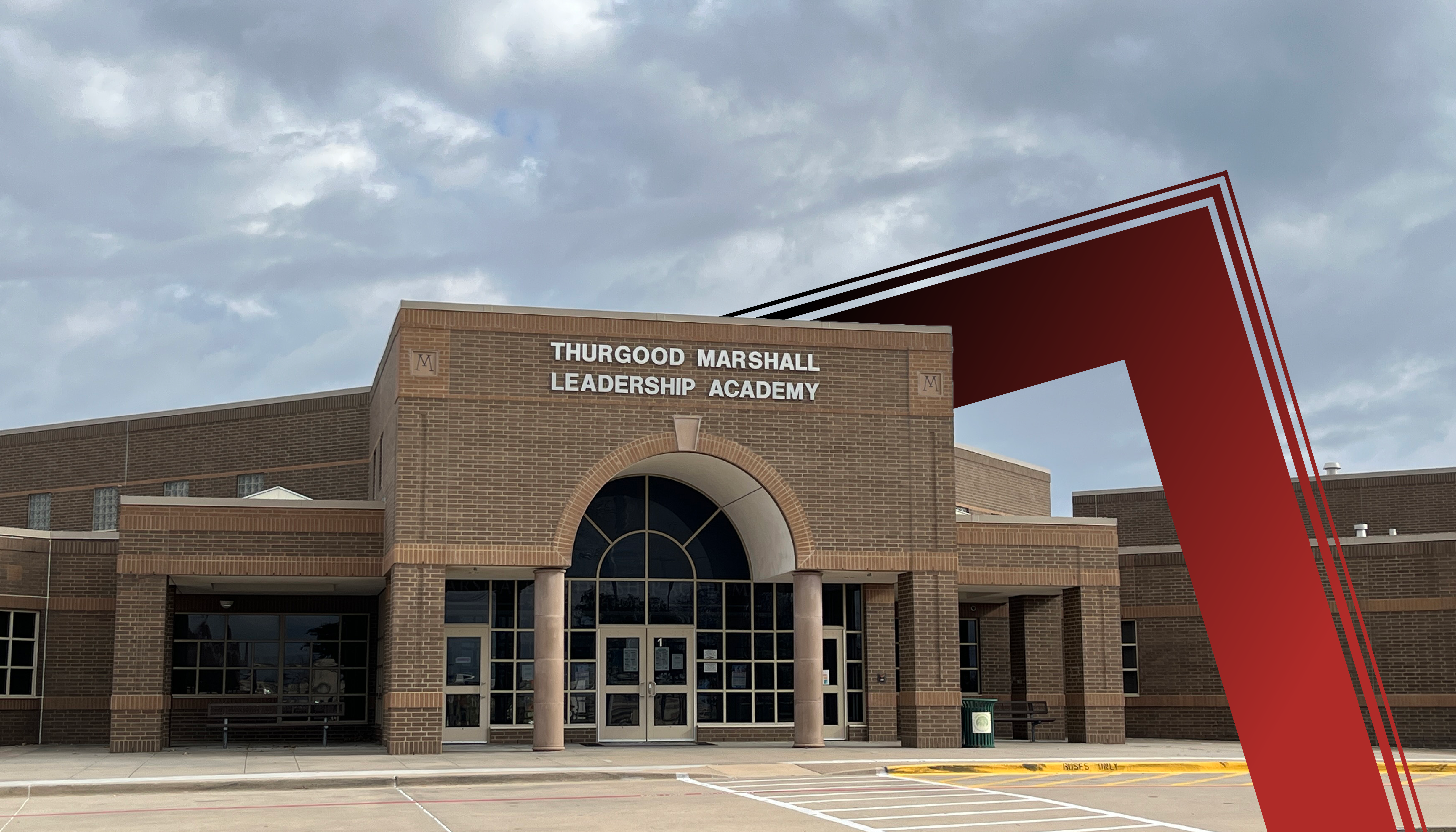 The image shows a large brick building with a prominent red sign that reads "Thurgood Marshall Leadership Academy". The building has a modern architectural design with large windows and a distinctive arched entrance. The sky in the background appears cloudy, adding to the overall atmosphere of the scene.
