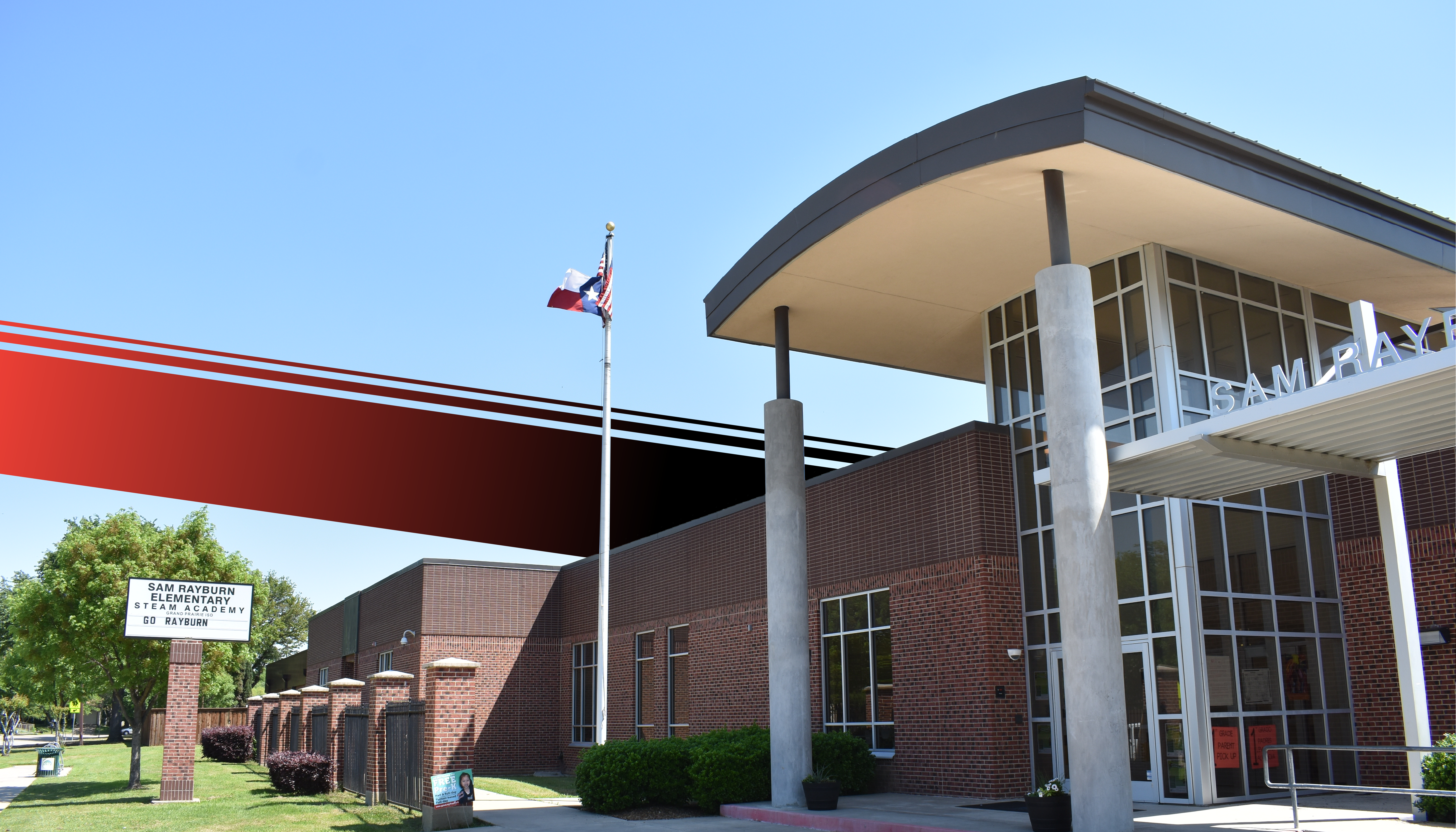 A modern brick building with a red and white flag pole in the foreground, surrounded by a grassy area and trees in the background.
