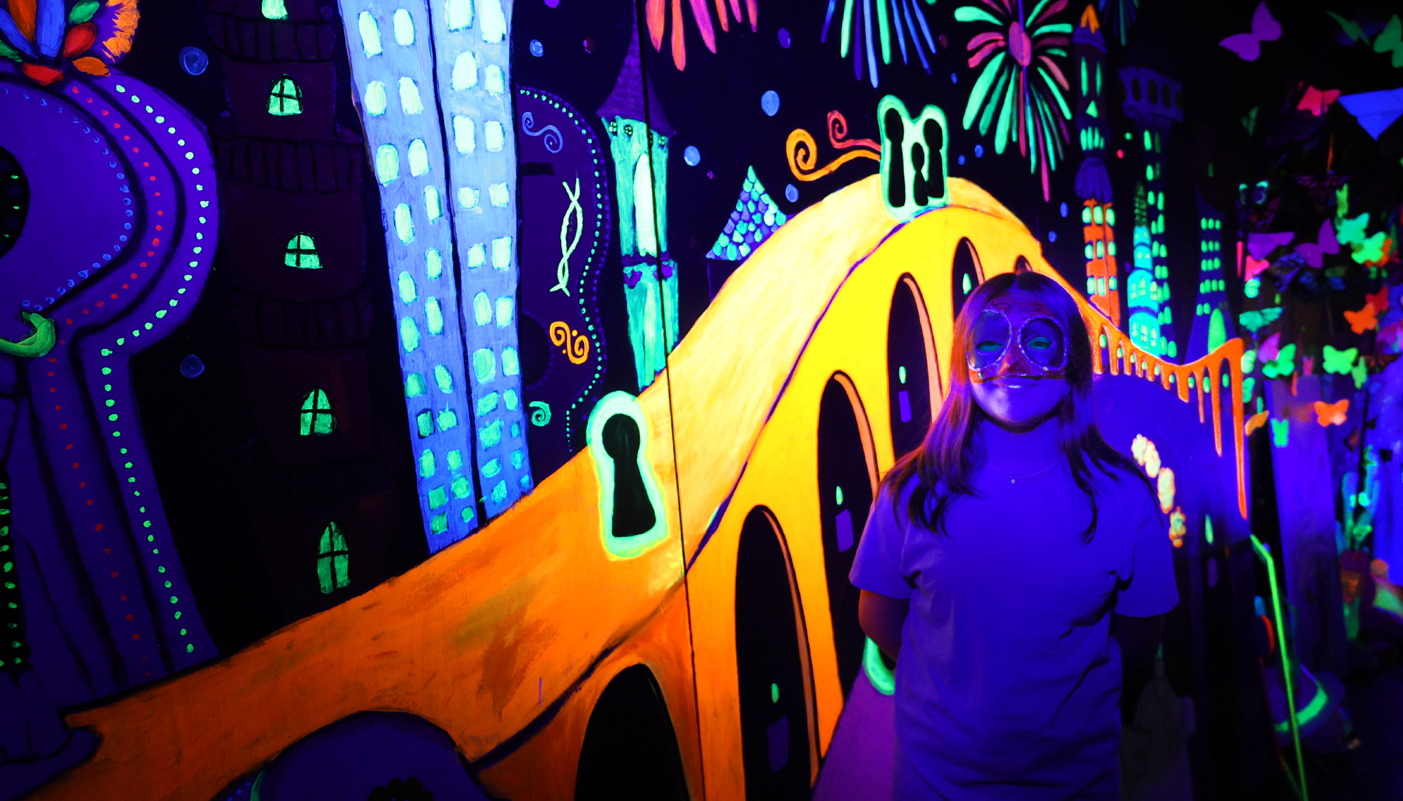 A vibrant, psychedelic scene with colorful, abstract shapes and patterns in the background, and a large, yellow, cartoonish figure in the foreground.