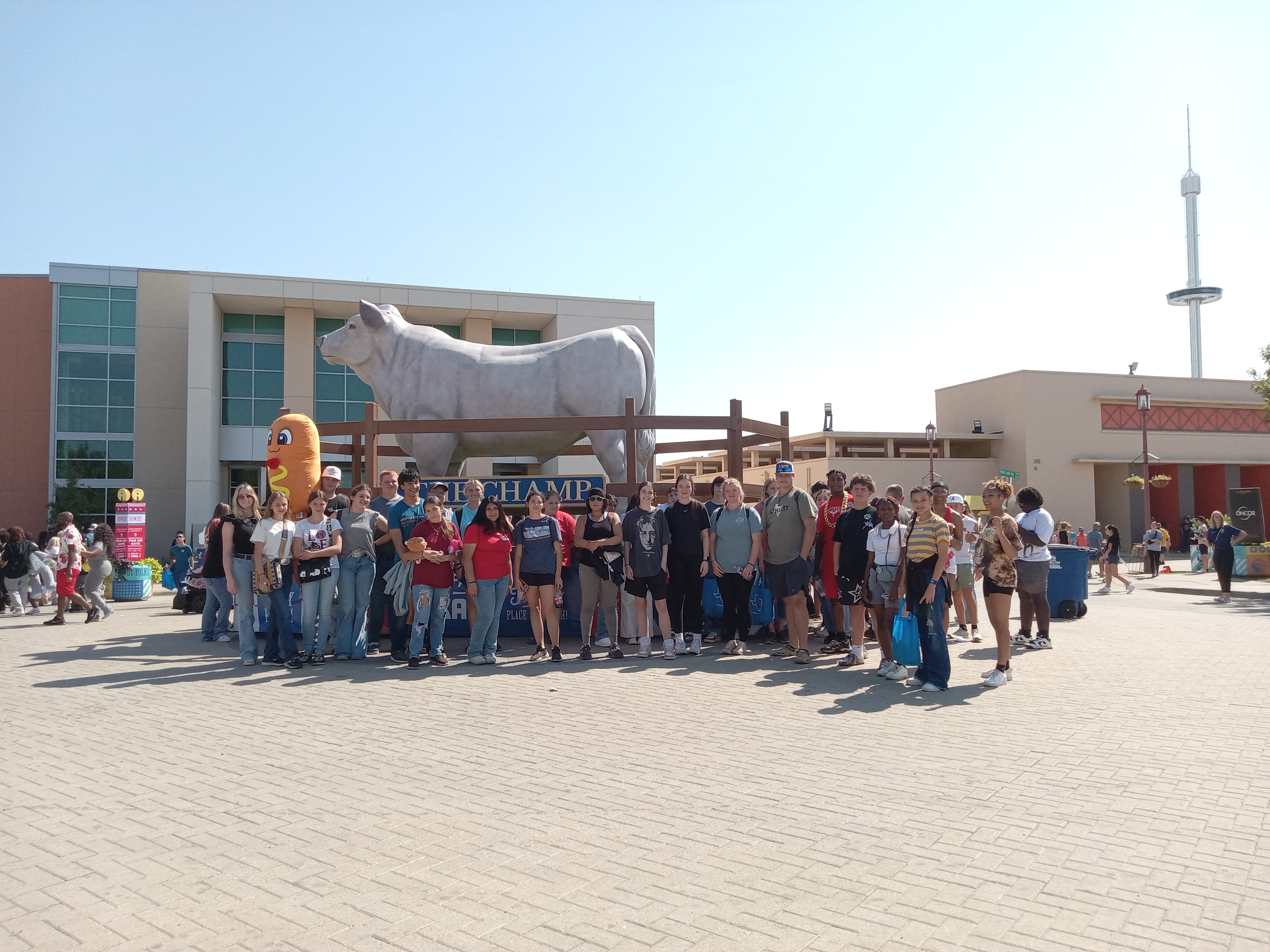 Group of many students standing in front of a cow statue