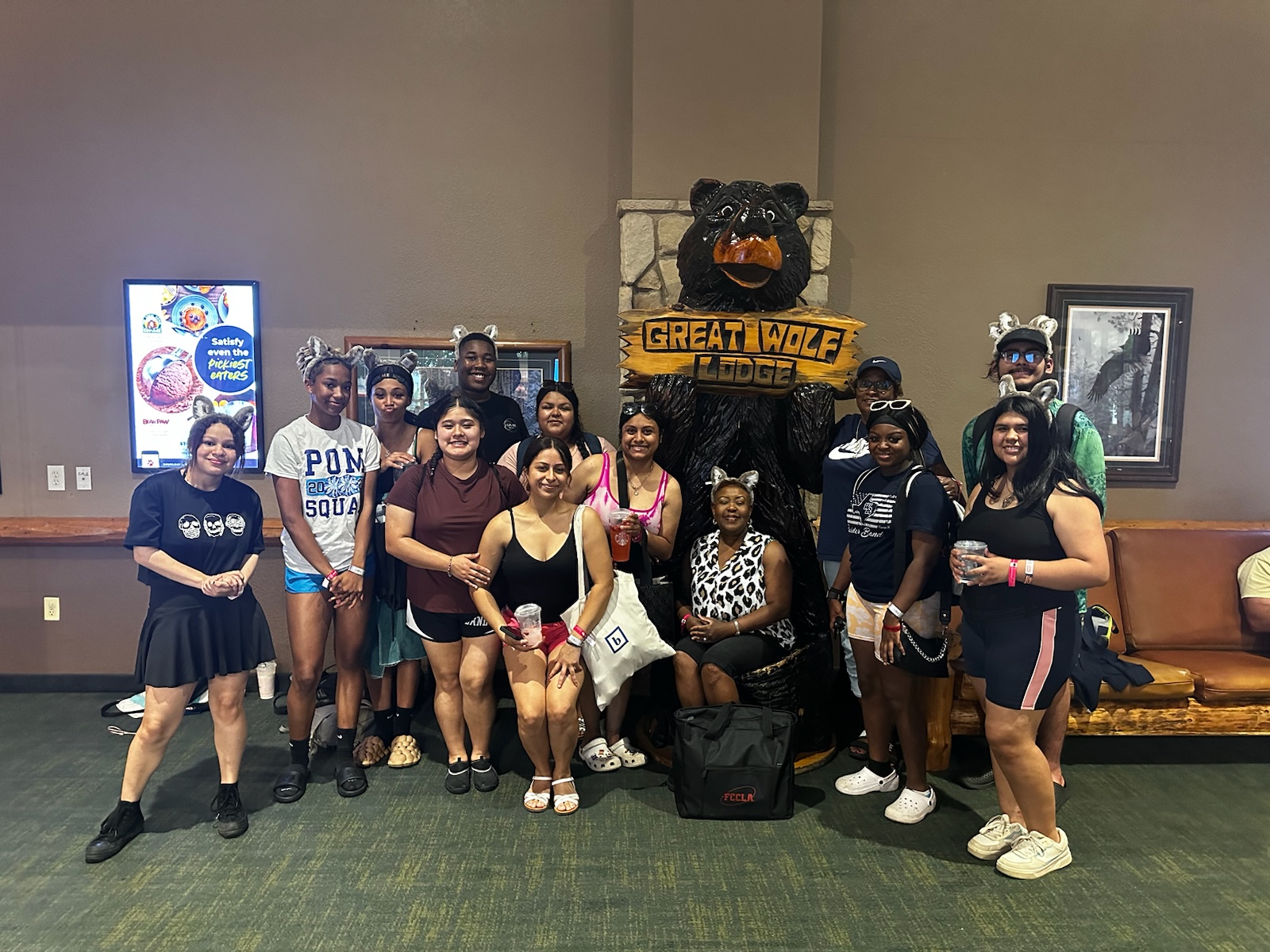 A group of students standing in front of a bear statue at Great Wolf Lodge
