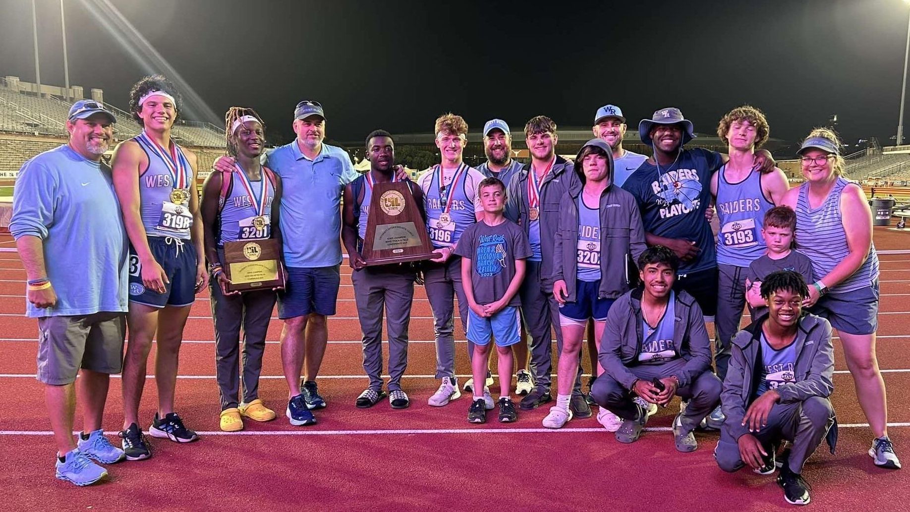 West Rusk High School track athletes standing on the track with their coaches and a state trophy